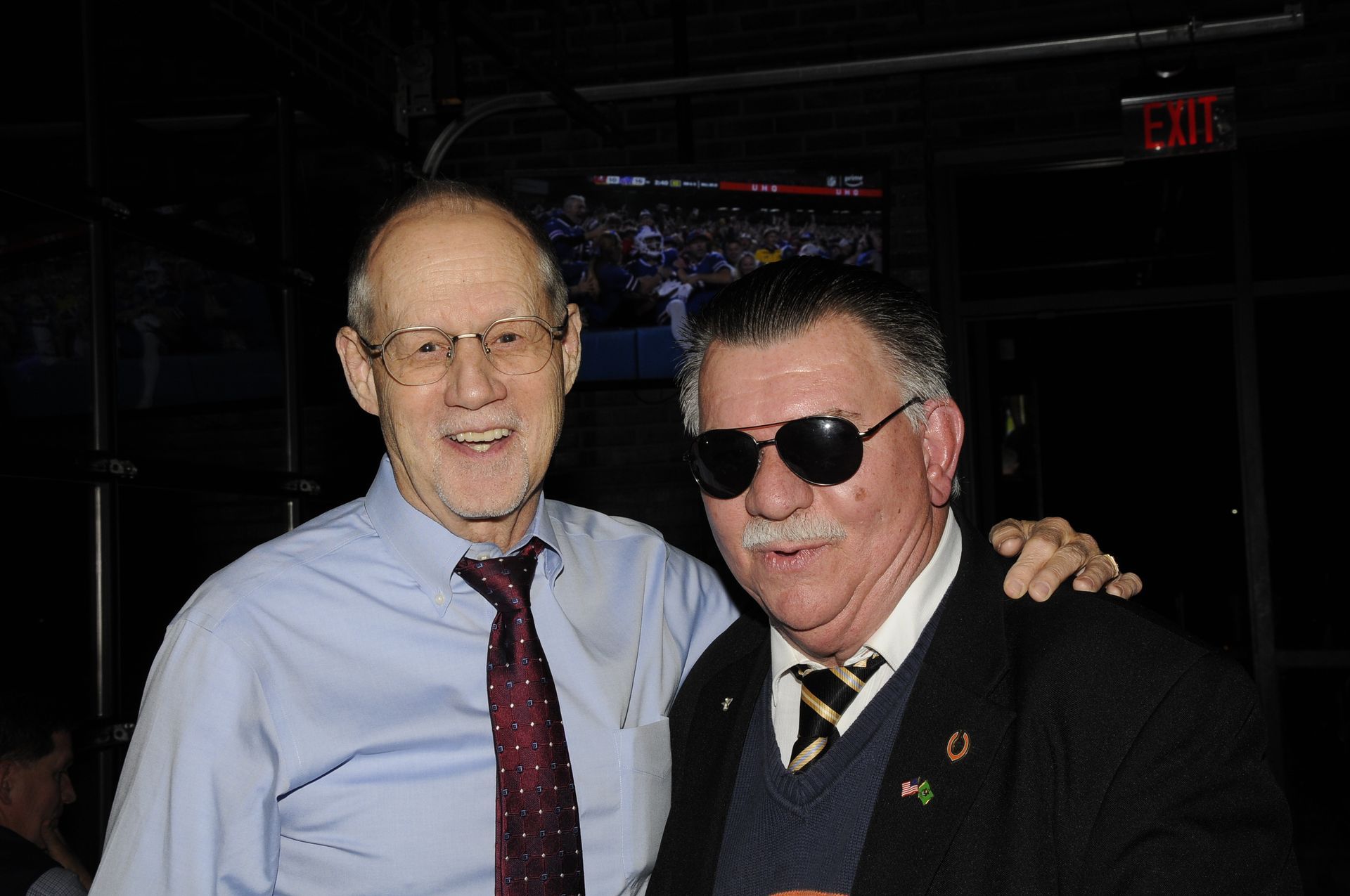 Two men posing for a picture with one wearing sunglasses