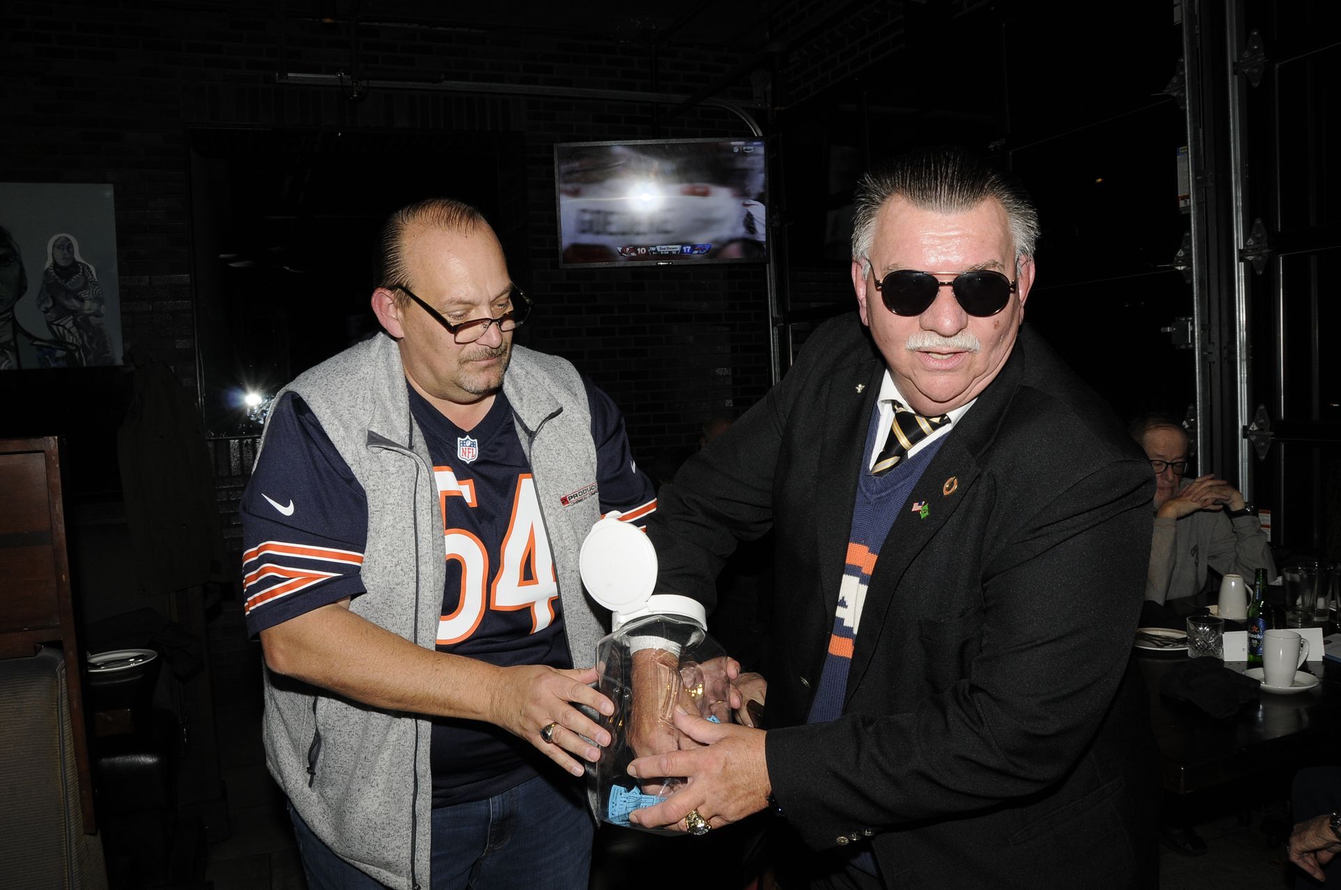 Two men are standing next to each other and one of them is wearing a jersey with the number 54 on it.