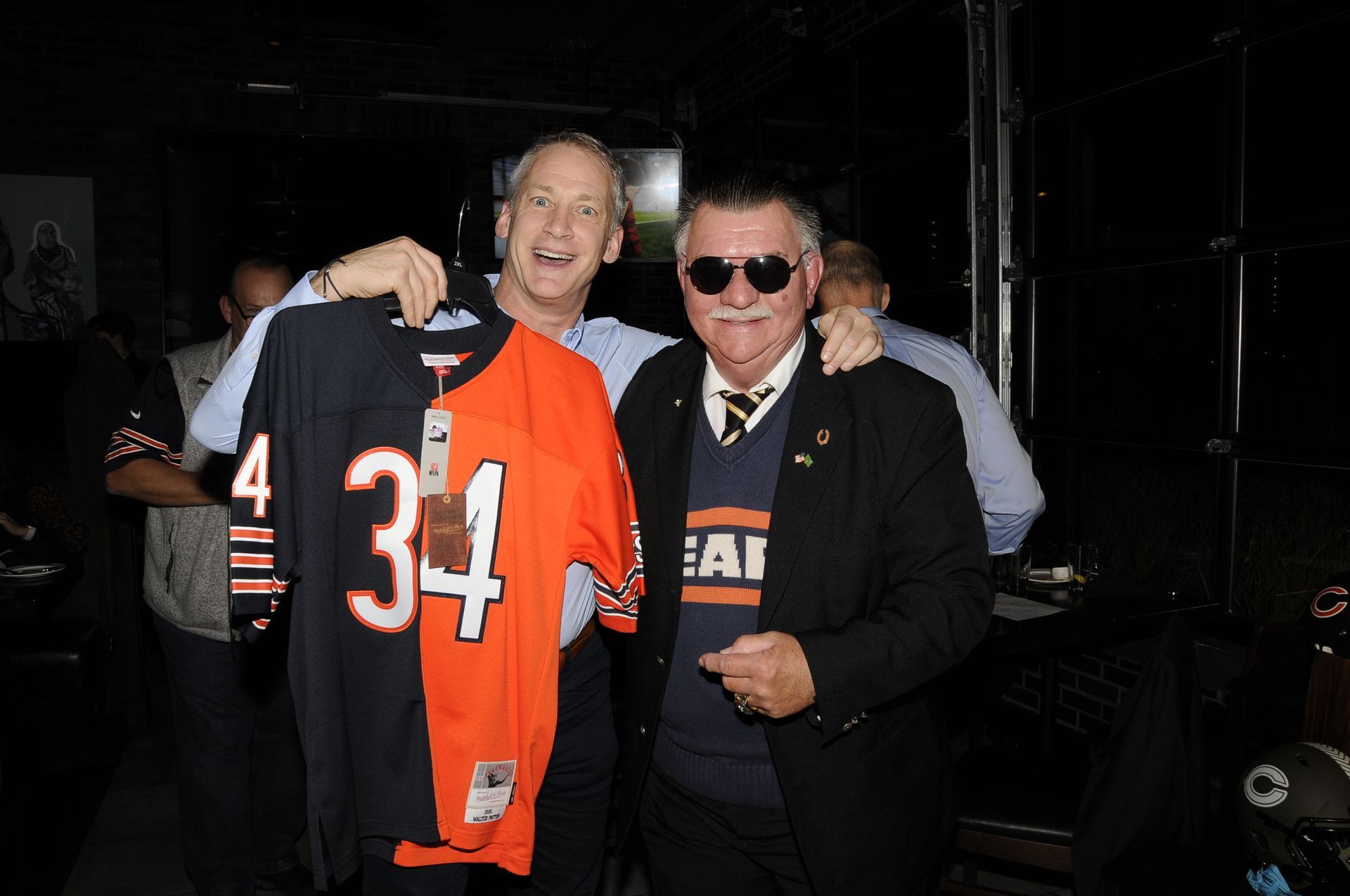Two men are standing next to each other holding a jersey with the number 34 on it.