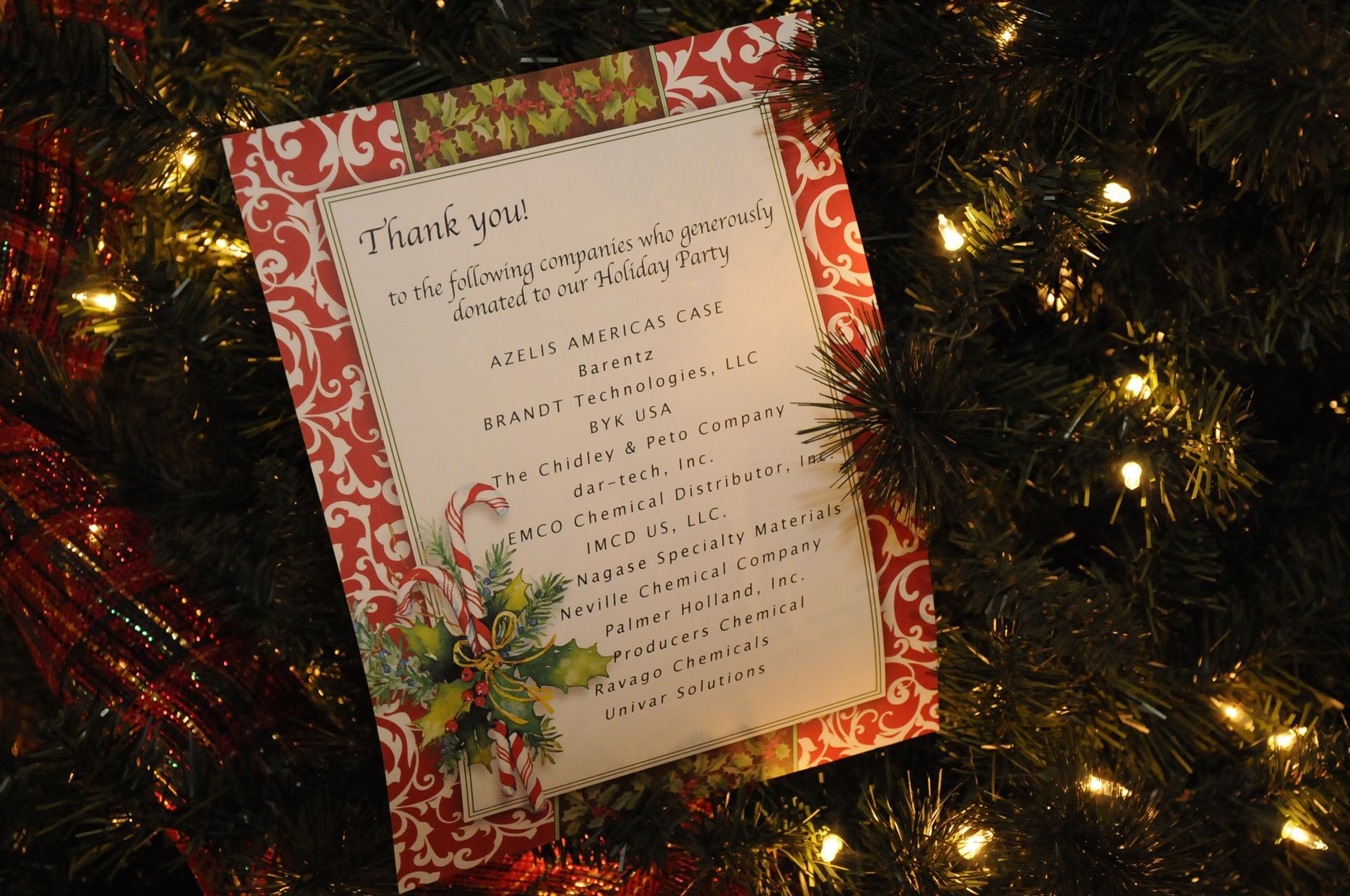 A thank you card is sitting in front of a christmas tree