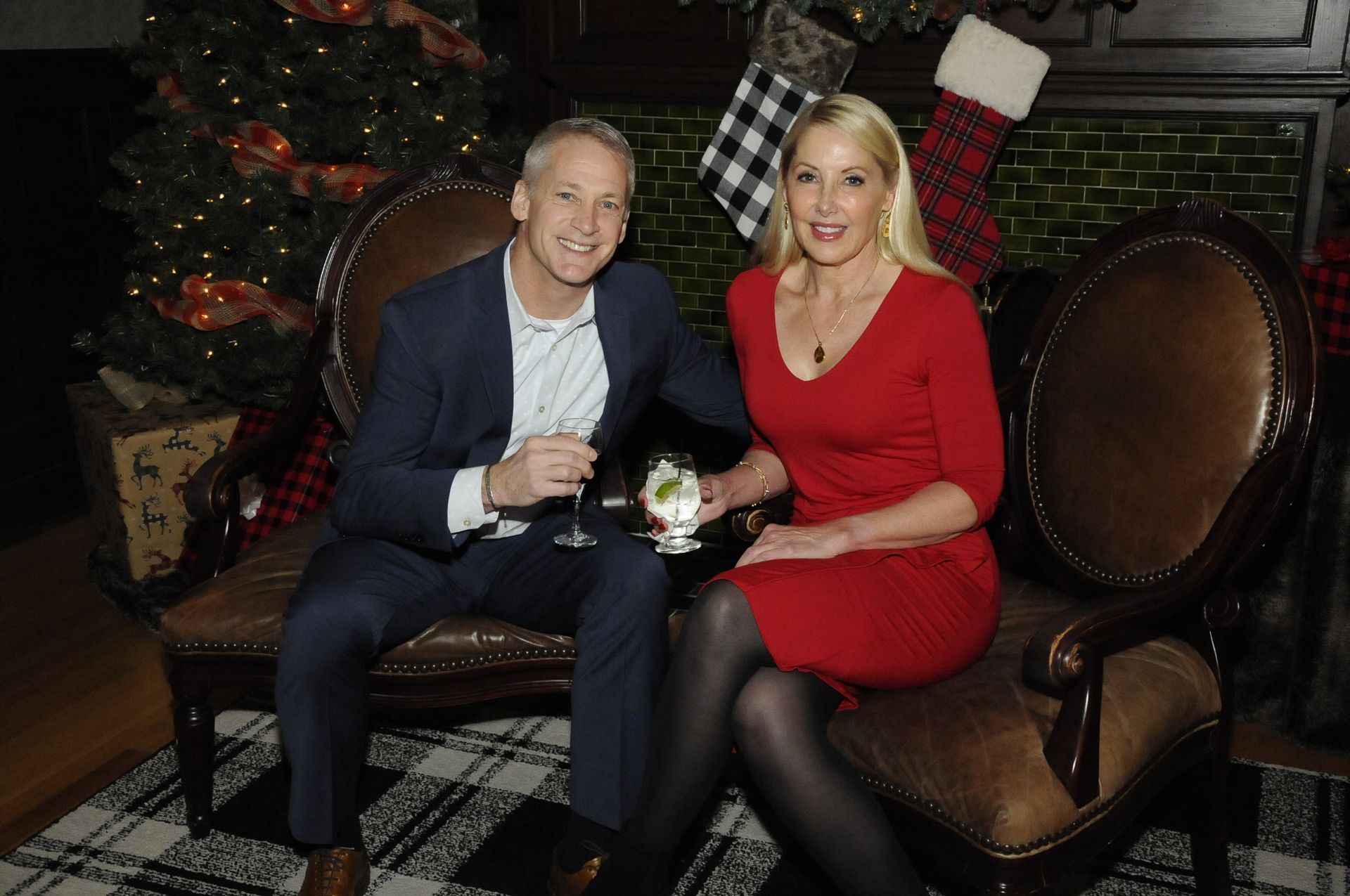 A man and a woman are sitting on a couch in front of a christmas tree.