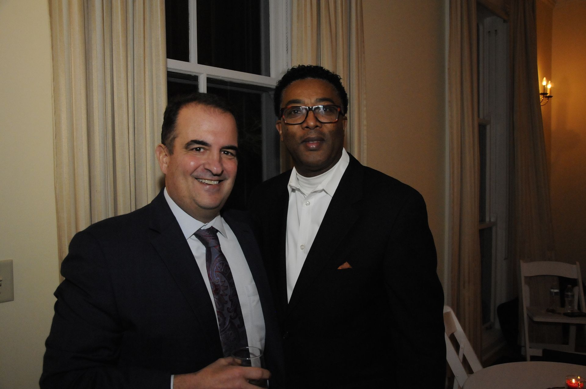 Two men in suits and ties are posing for a picture in a room.
