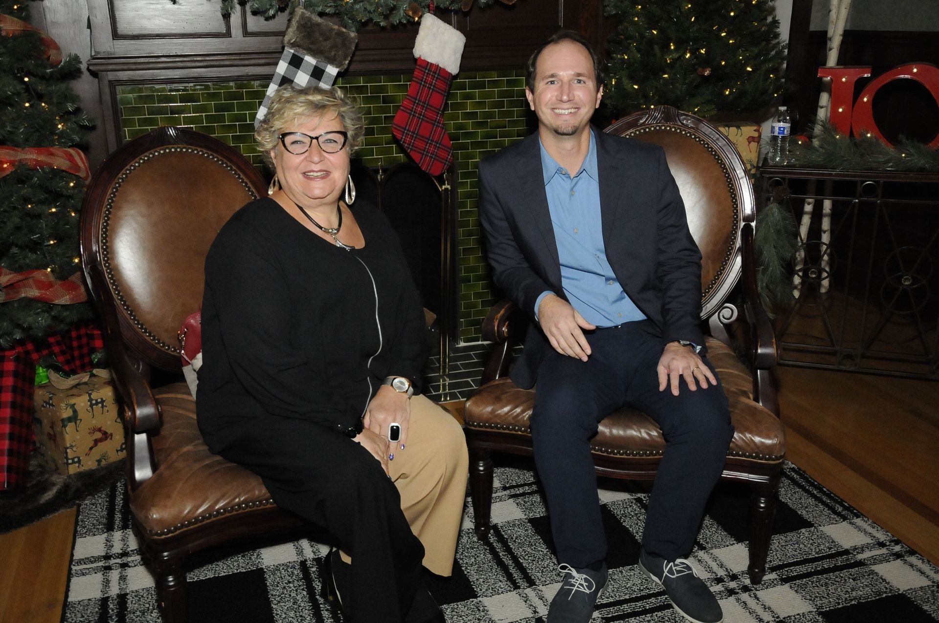 A man and a woman are sitting on a couch in front of a fireplace.