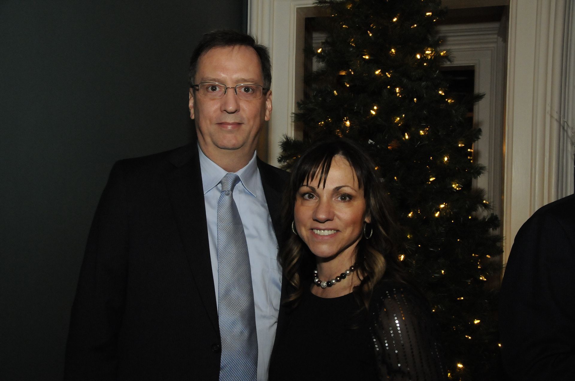 A man and a woman are posing for a picture in front of a christmas tree.