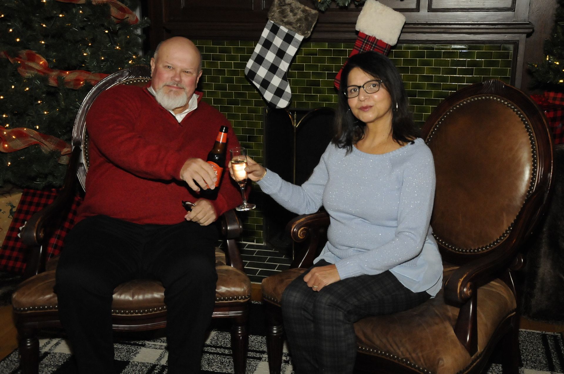 A man and a woman are sitting in chairs in front of a fireplace.