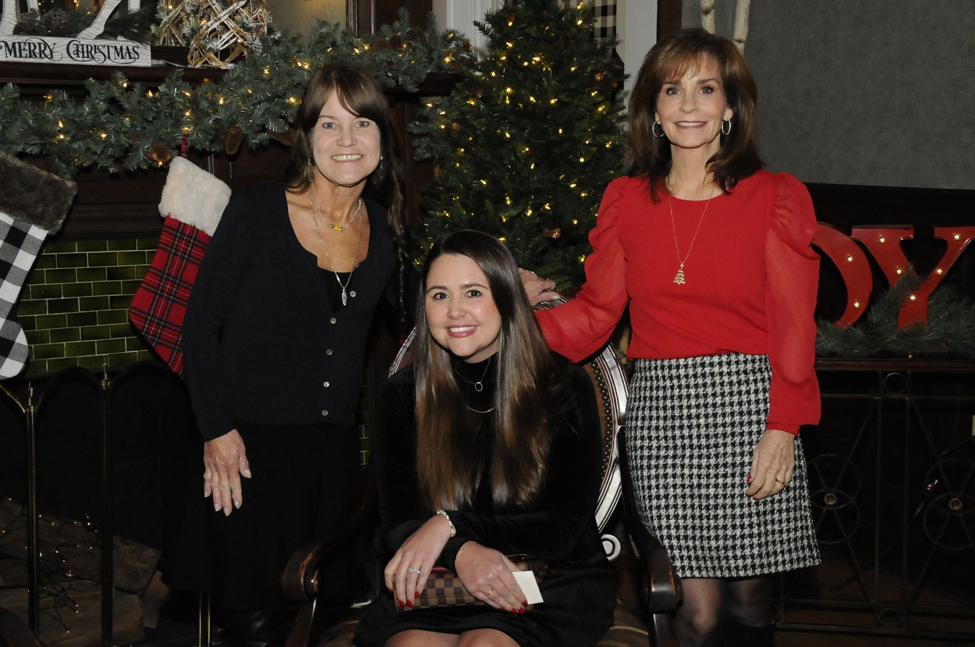 Three women are posing for a picture in front of a christmas tree.