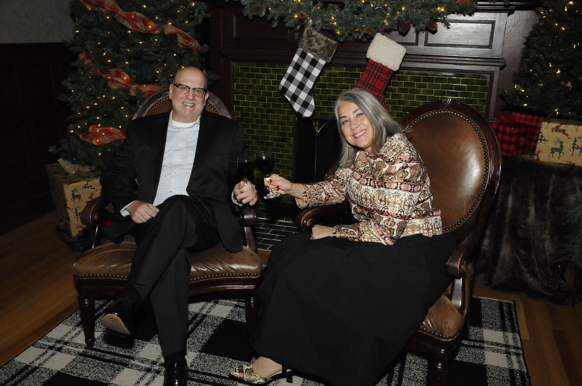 A man and a woman are sitting in chairs in front of a christmas tree.