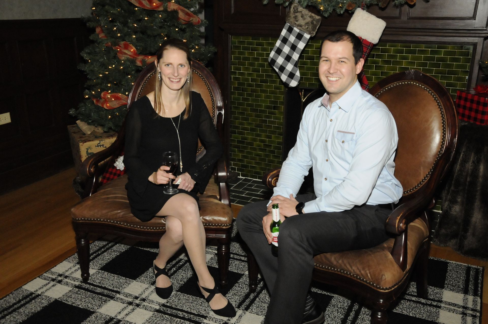 A man and a woman are sitting in chairs in front of a christmas tree