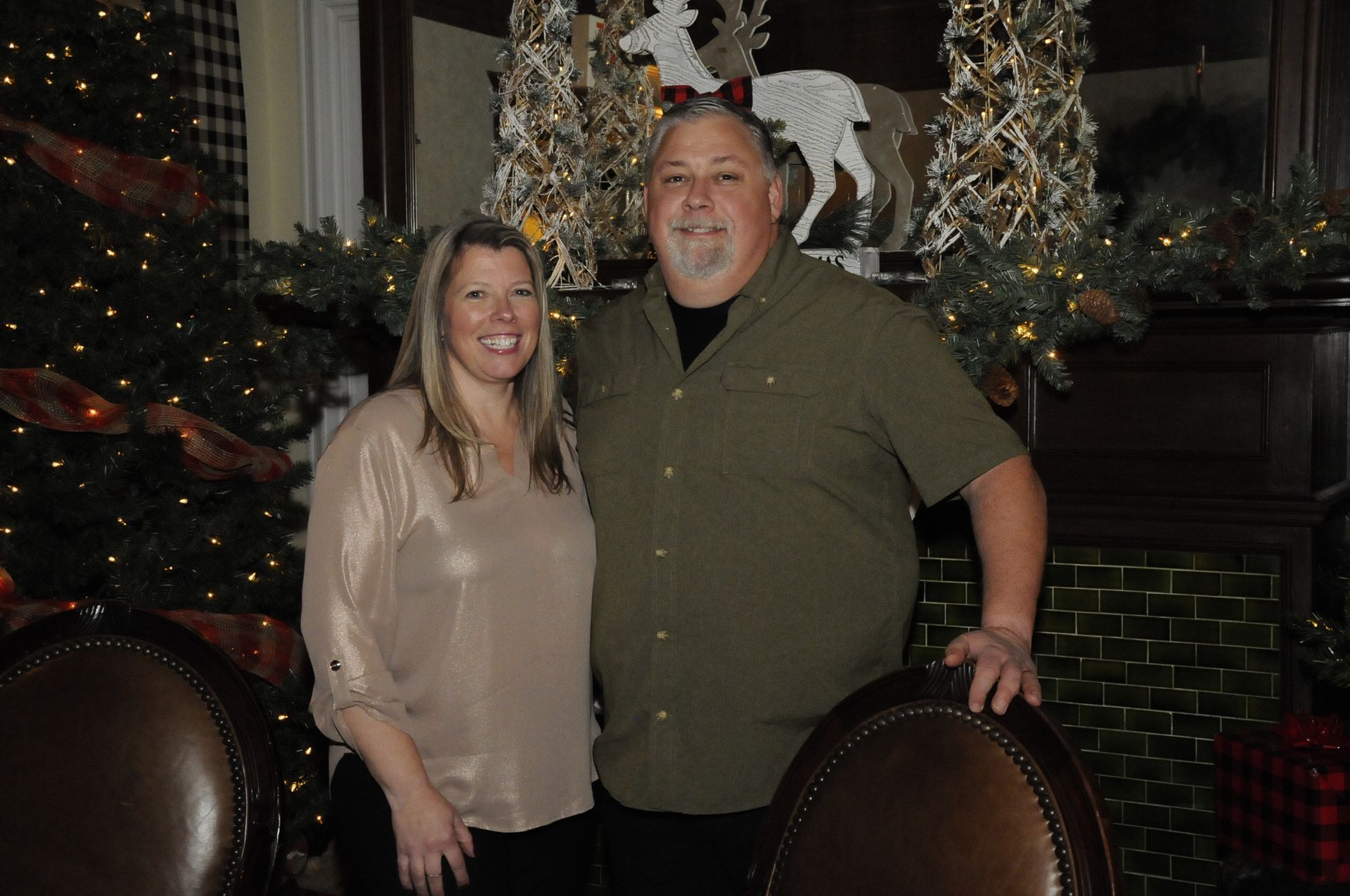 A man and a woman are posing for a picture in front of a christmas tree.