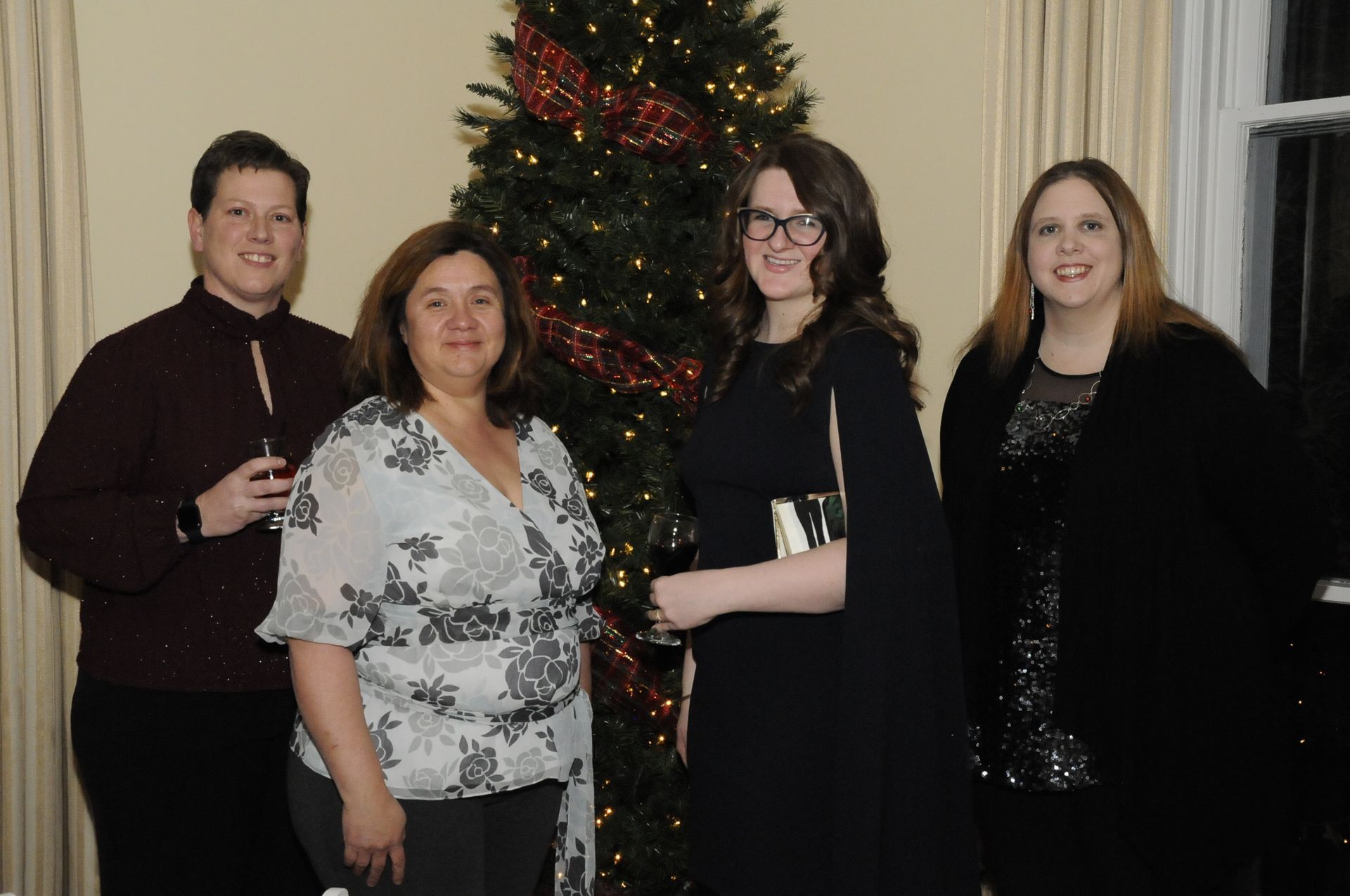 A group of people are posing for a picture in front of a christmas tree.