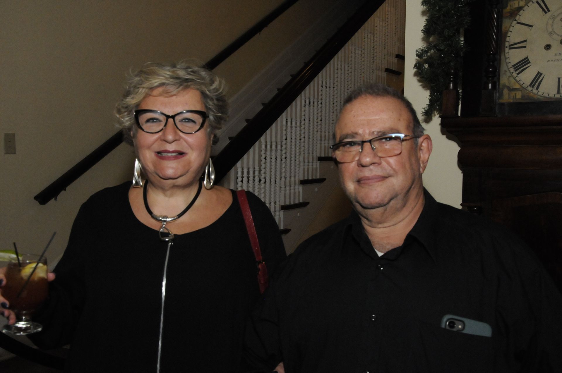 A man and a woman are posing for a picture in front of a staircase.