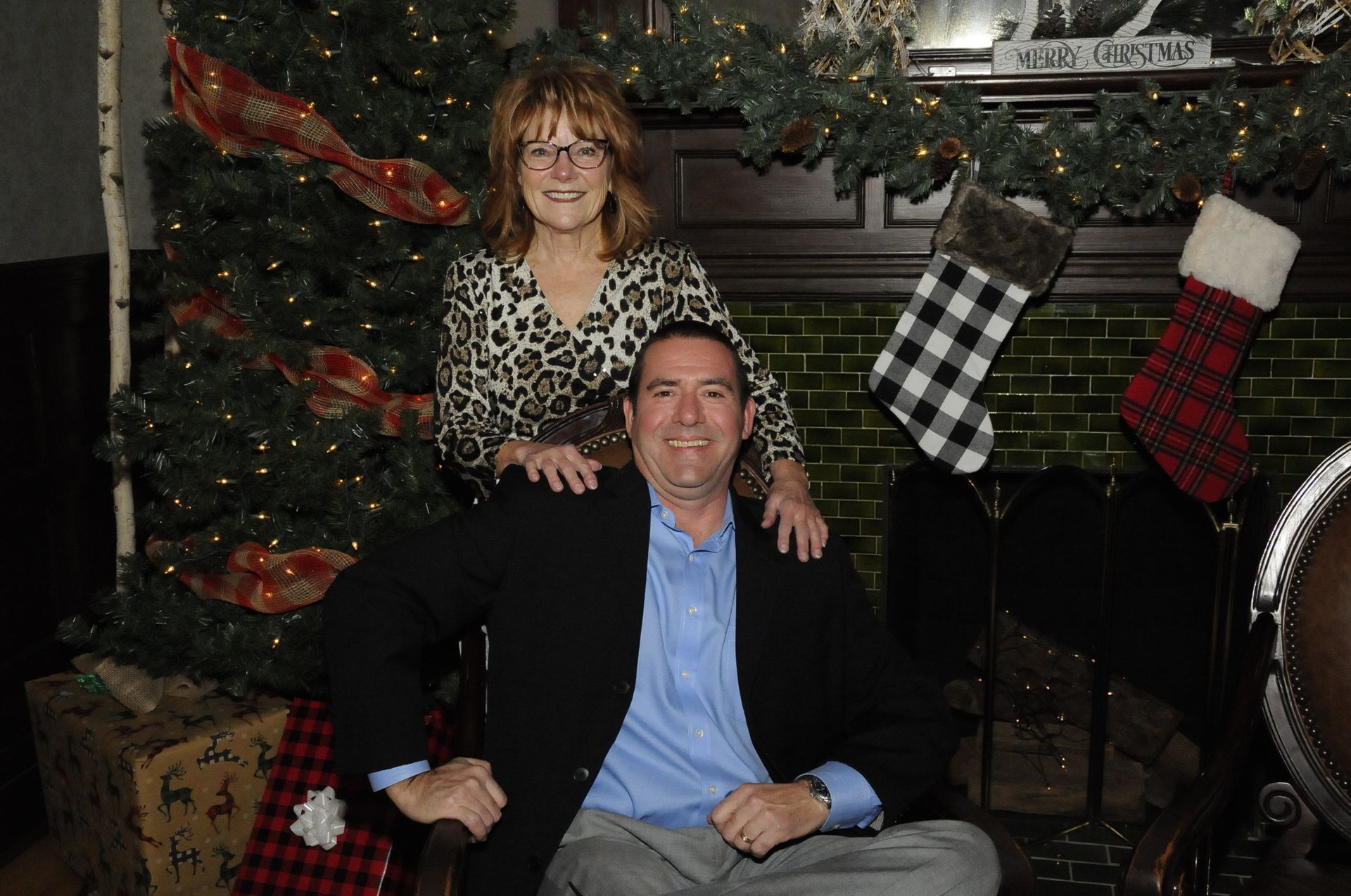 A man and a woman are posing for a picture in front of a christmas tree.