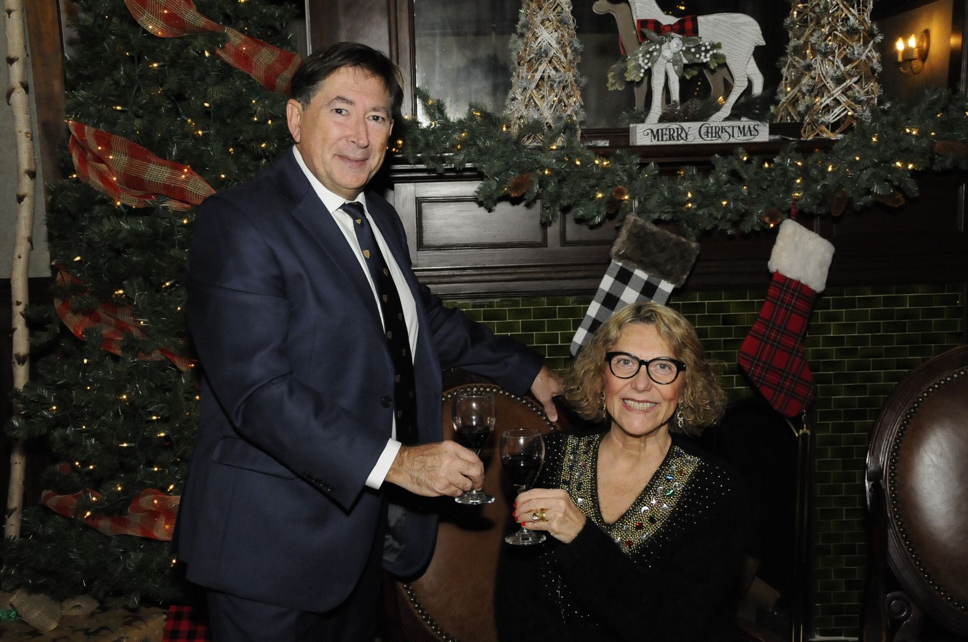 A man and a woman are standing next to each other in front of a christmas tree.