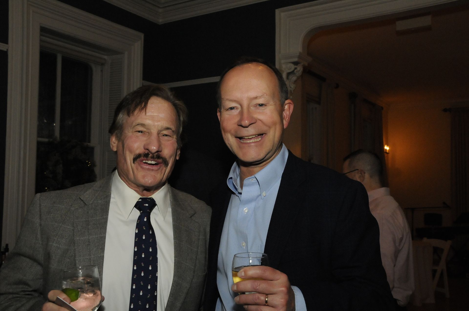 Two men are posing for a picture while holding glasses of wine.