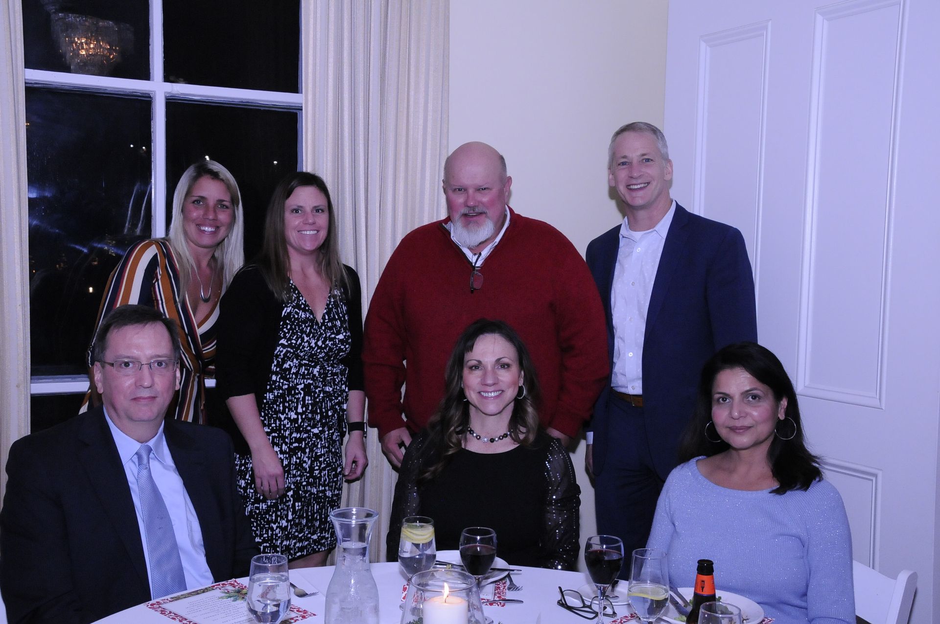 A group of people are posing for a picture while sitting at a table.