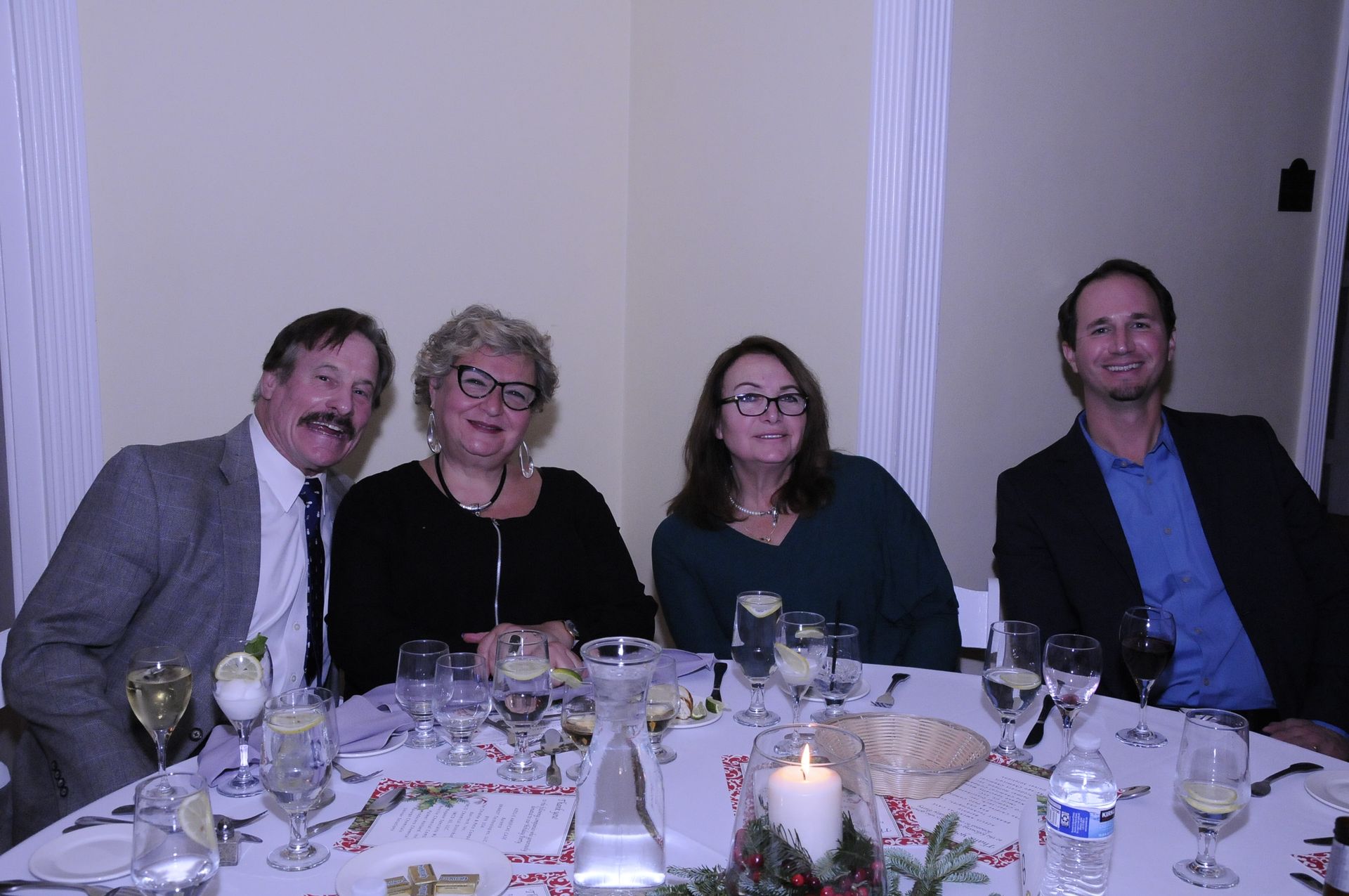 A group of people are sitting at a table with wine glasses and a candle.
