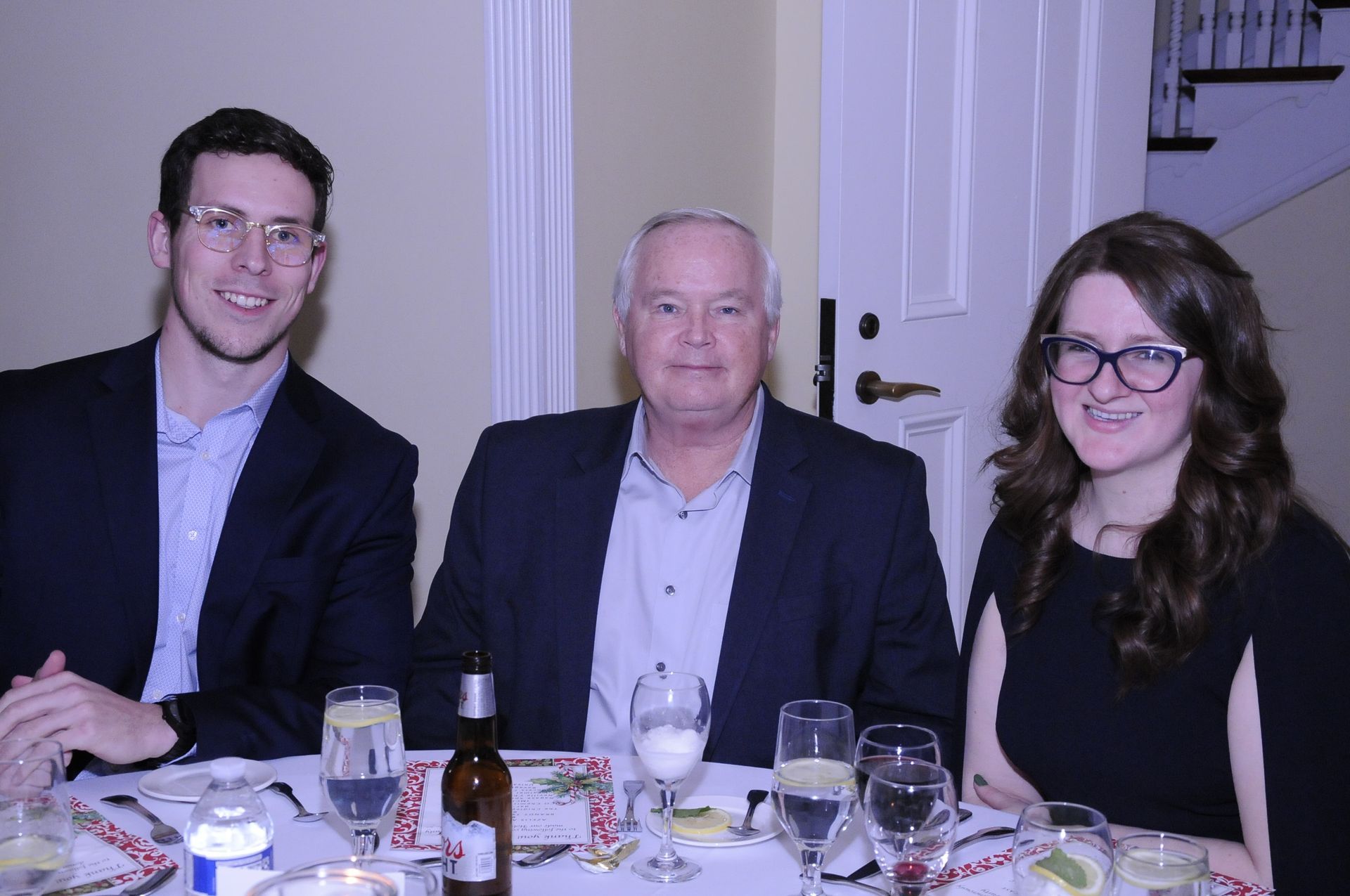 A man and two women are sitting at a table with wine glasses.