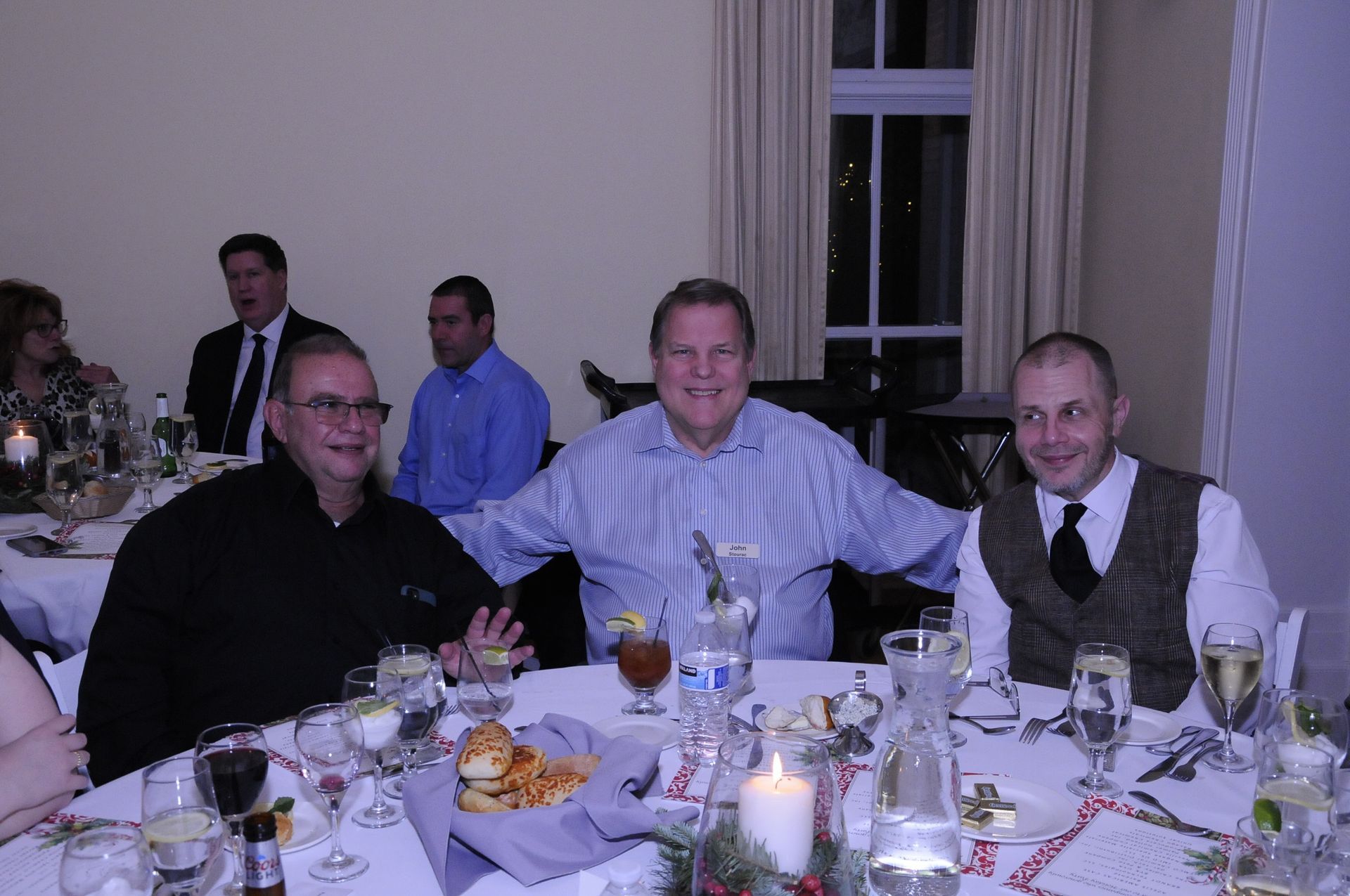 A group of men are sitting at a table with wine glasses and a candle.