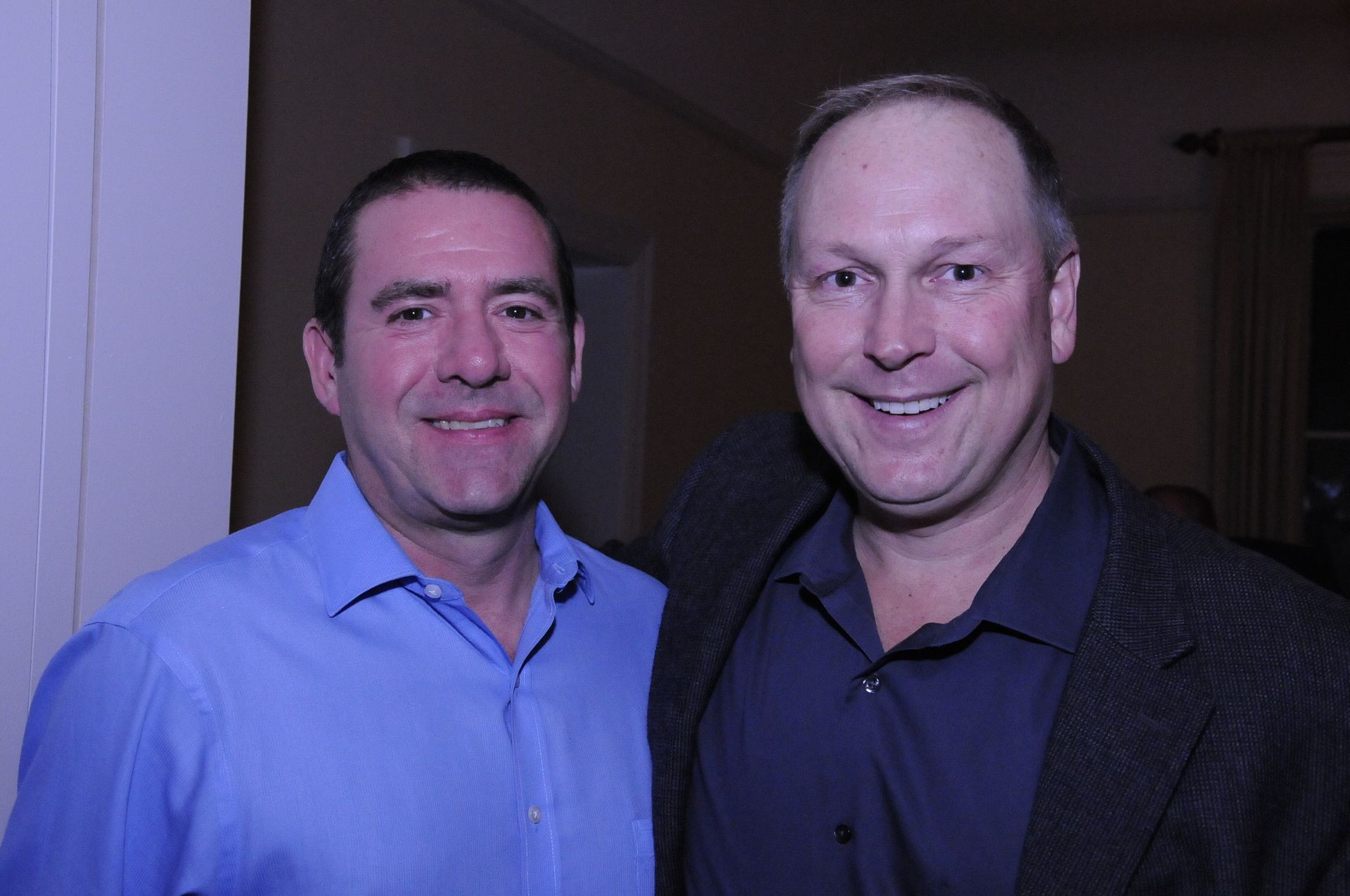 Two men are posing for a picture together and smiling for the camera.