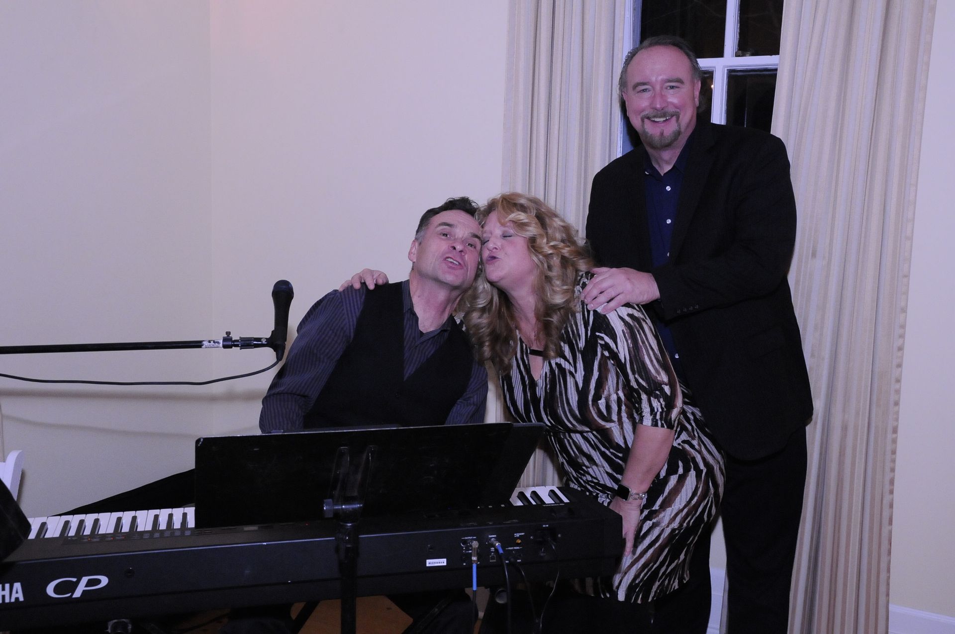 A woman is kissing a man on the cheek in front of a piano.