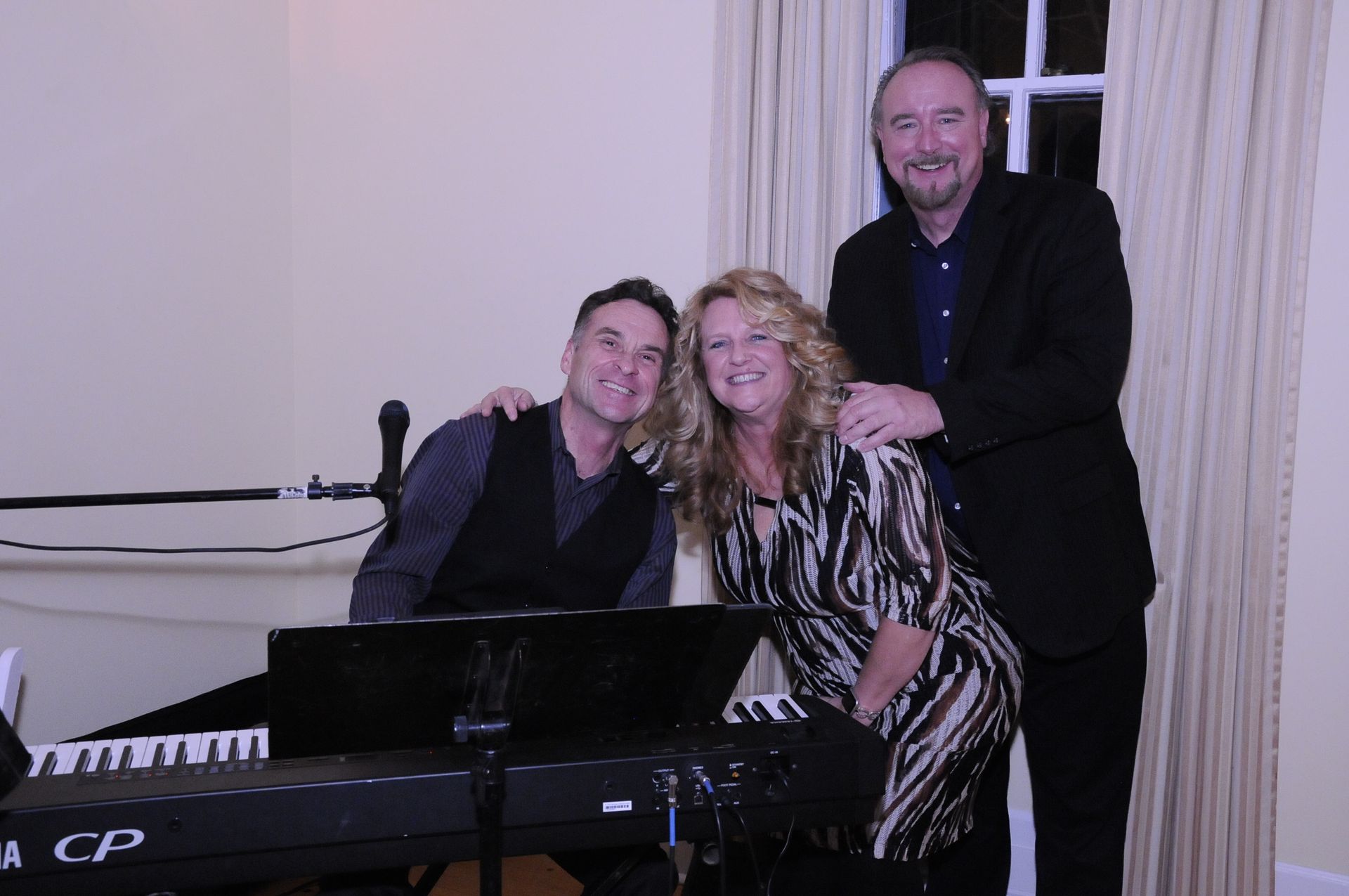 Three people are posing for a picture in front of a piano.