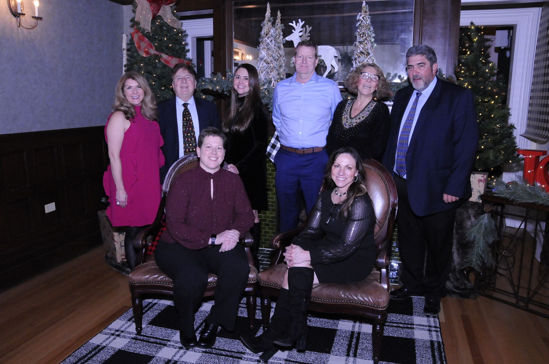 A group of people are posing for a picture in front of a christmas tree.