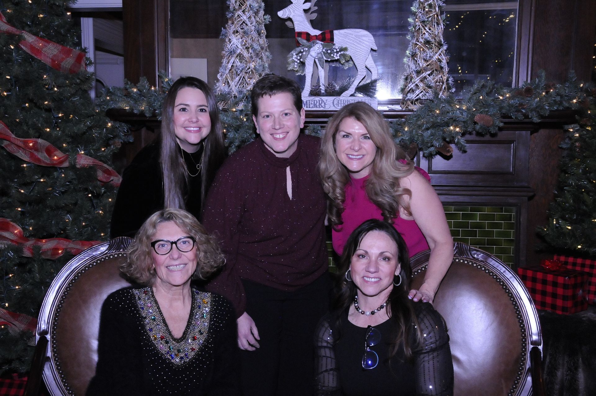 A group of women are posing for a picture in front of a christmas tree.
