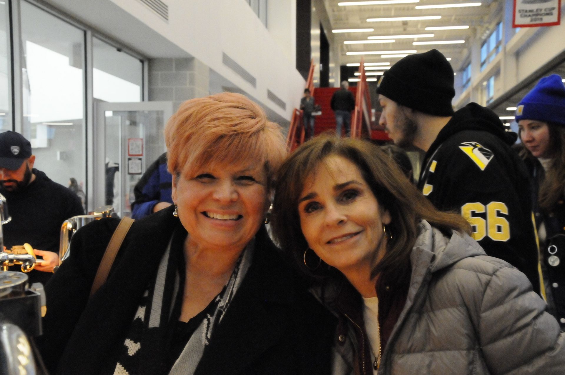 Two women posing for a picture with one wearing a jacket with the number 56 on it
