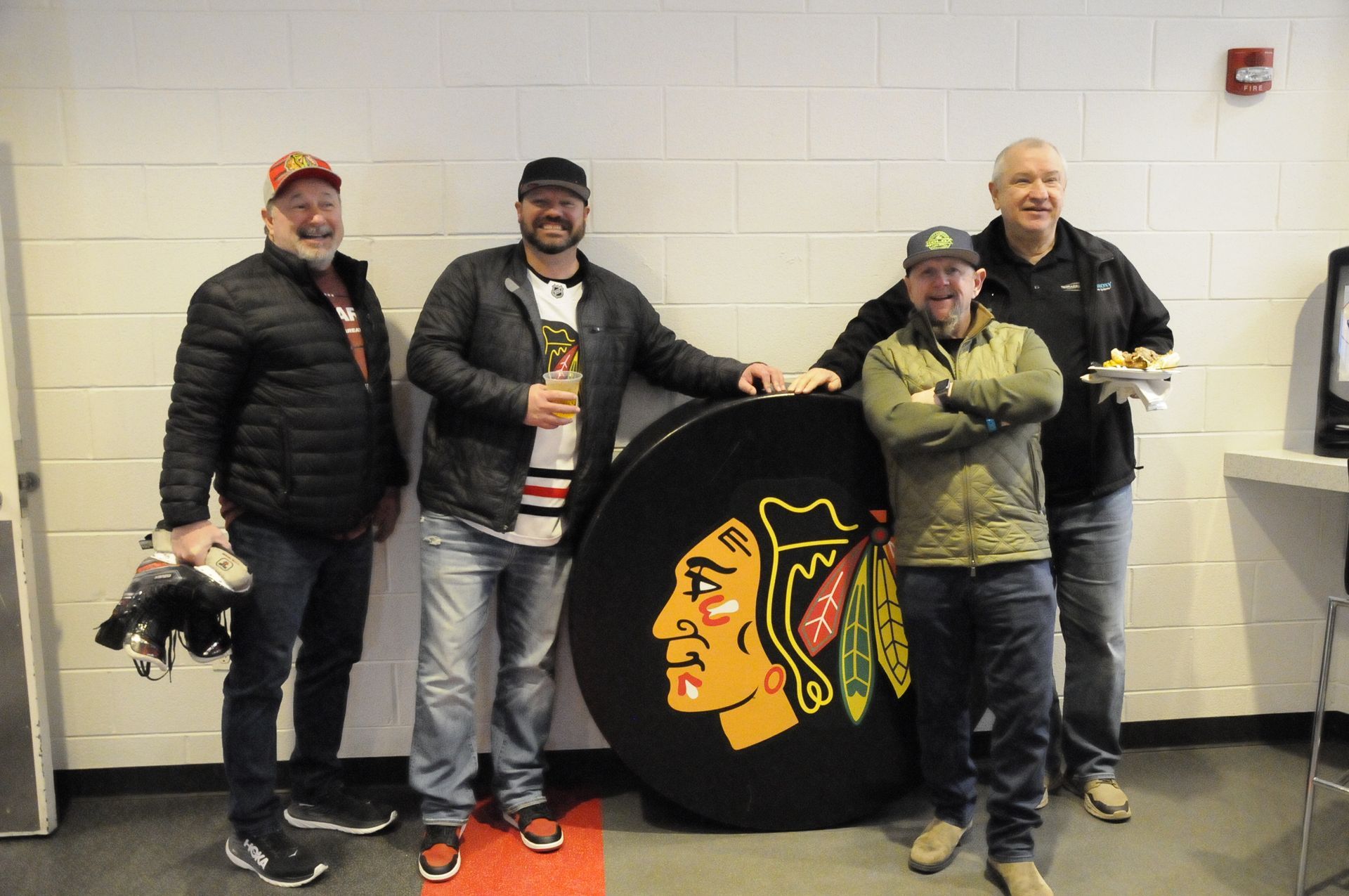 A group of men are standing next to a large blackhawks logo.