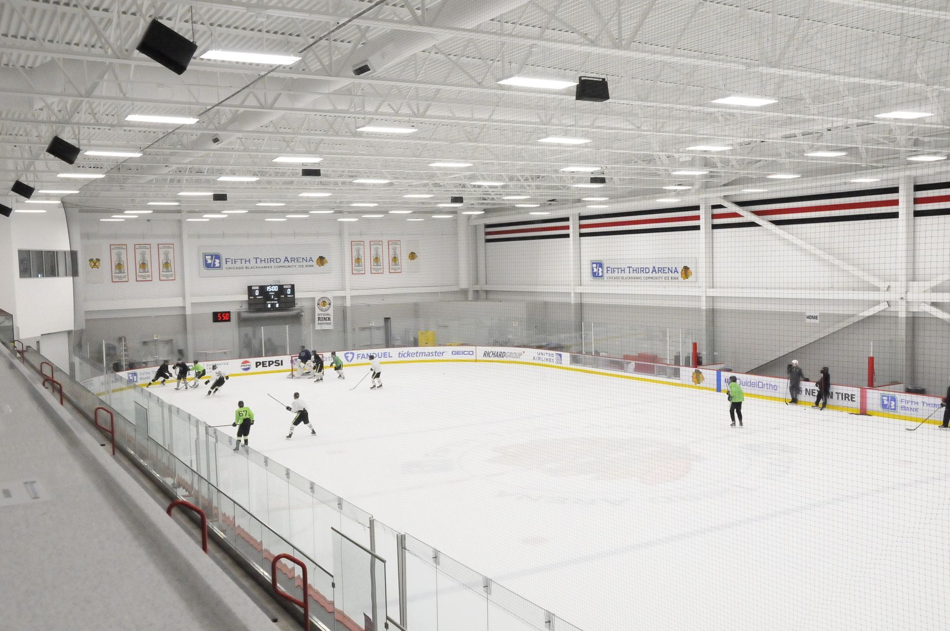 A group of people are playing ice hockey in a large indoor rink.