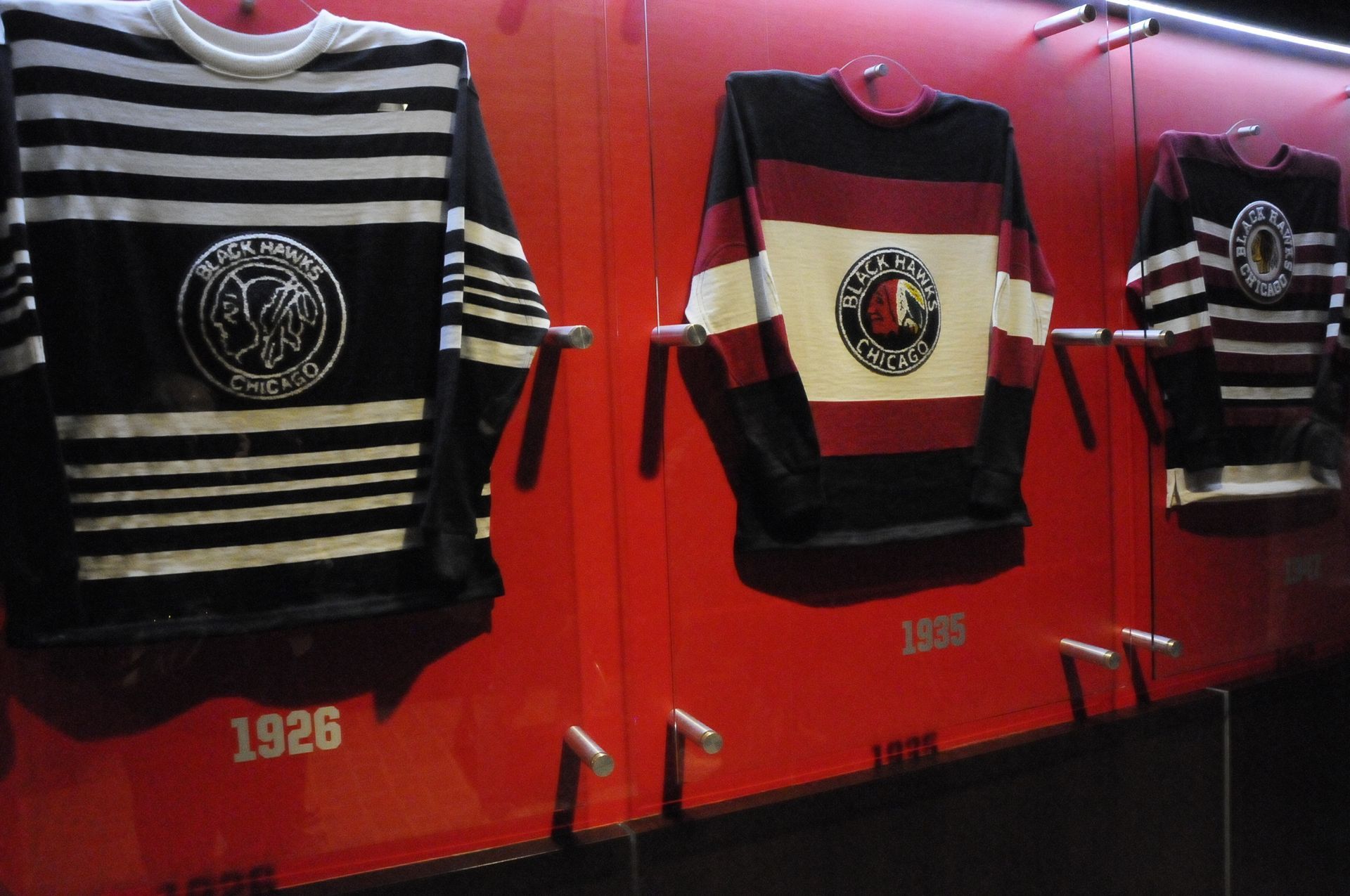 Three jerseys hanging on a red wall with the year 1925