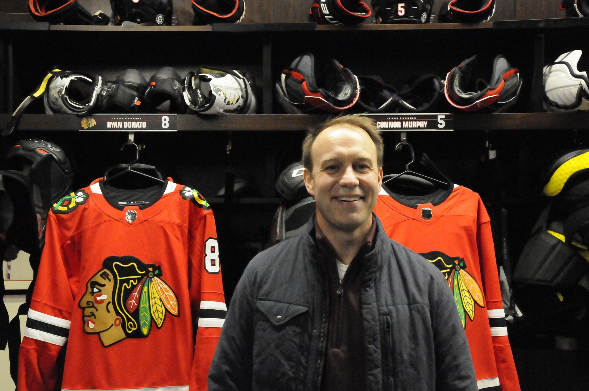 A man is standing in front of a hockey jersey with the number 8 on it