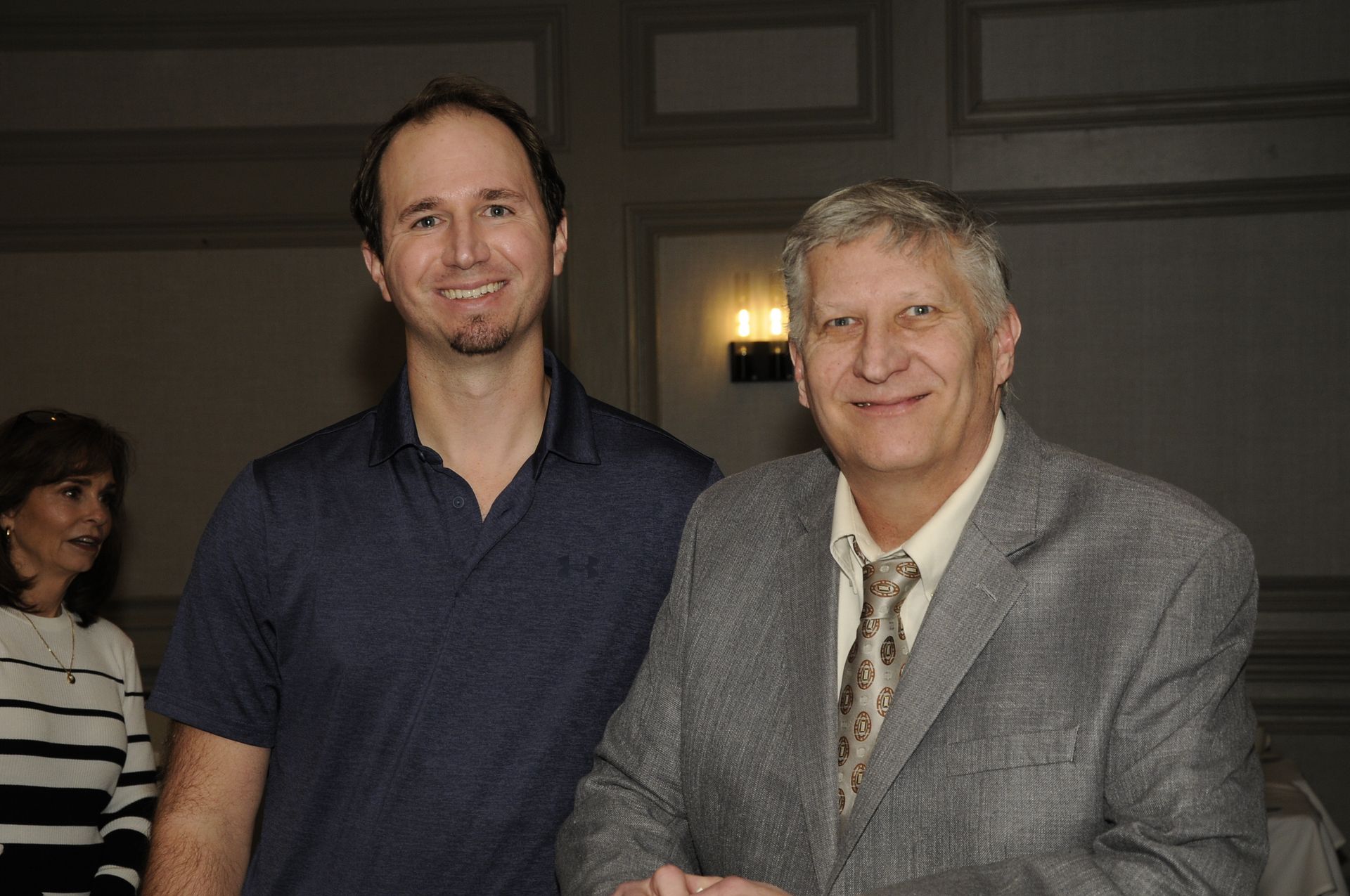 Two men are standing next to each other and shaking hands.