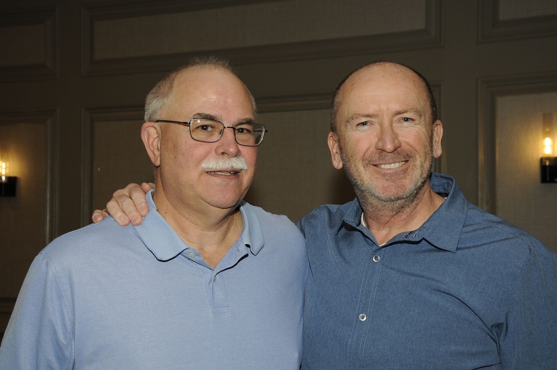 Two men are posing for a picture together in a room.