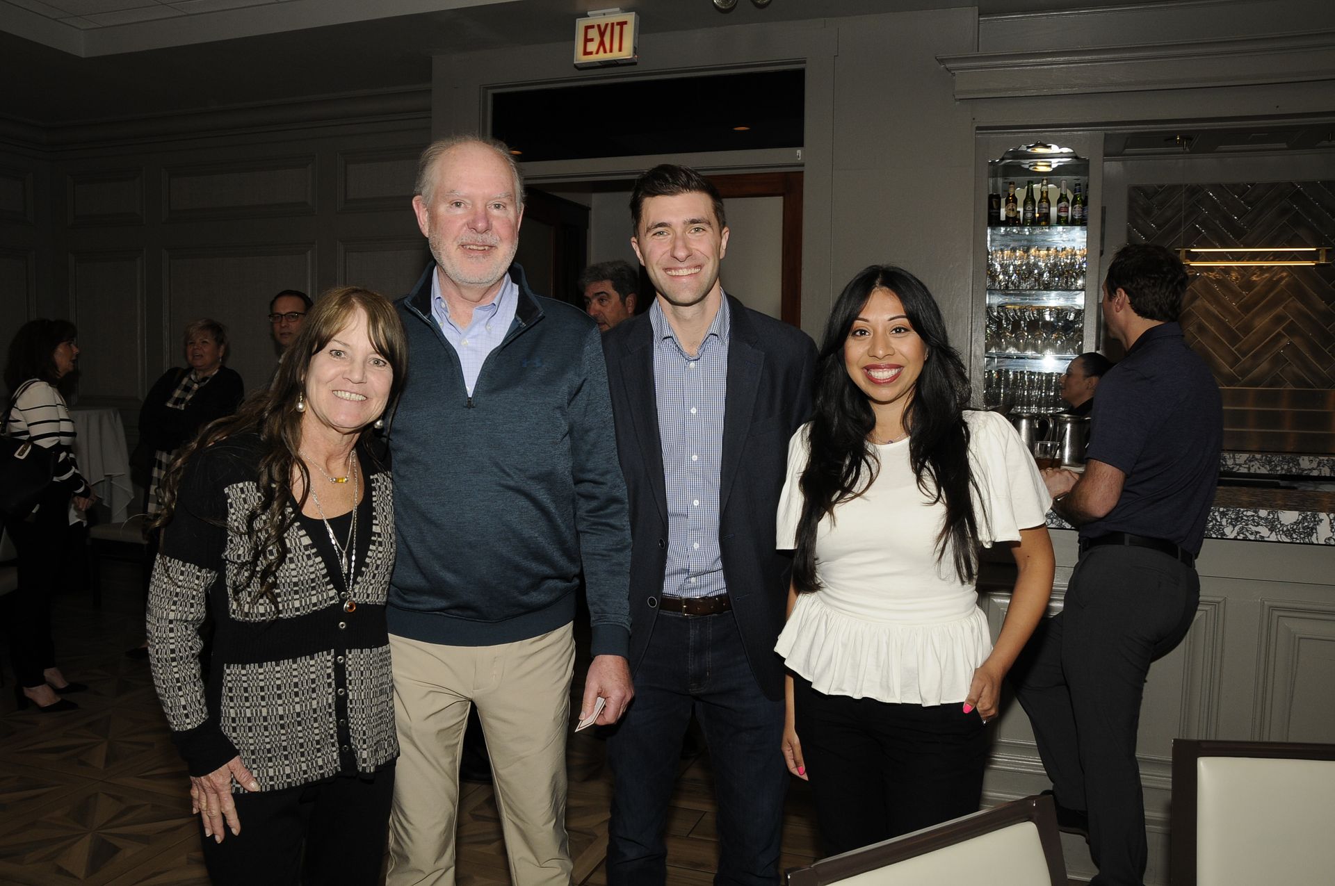 A group of people are posing for a picture in front of an exit sign.