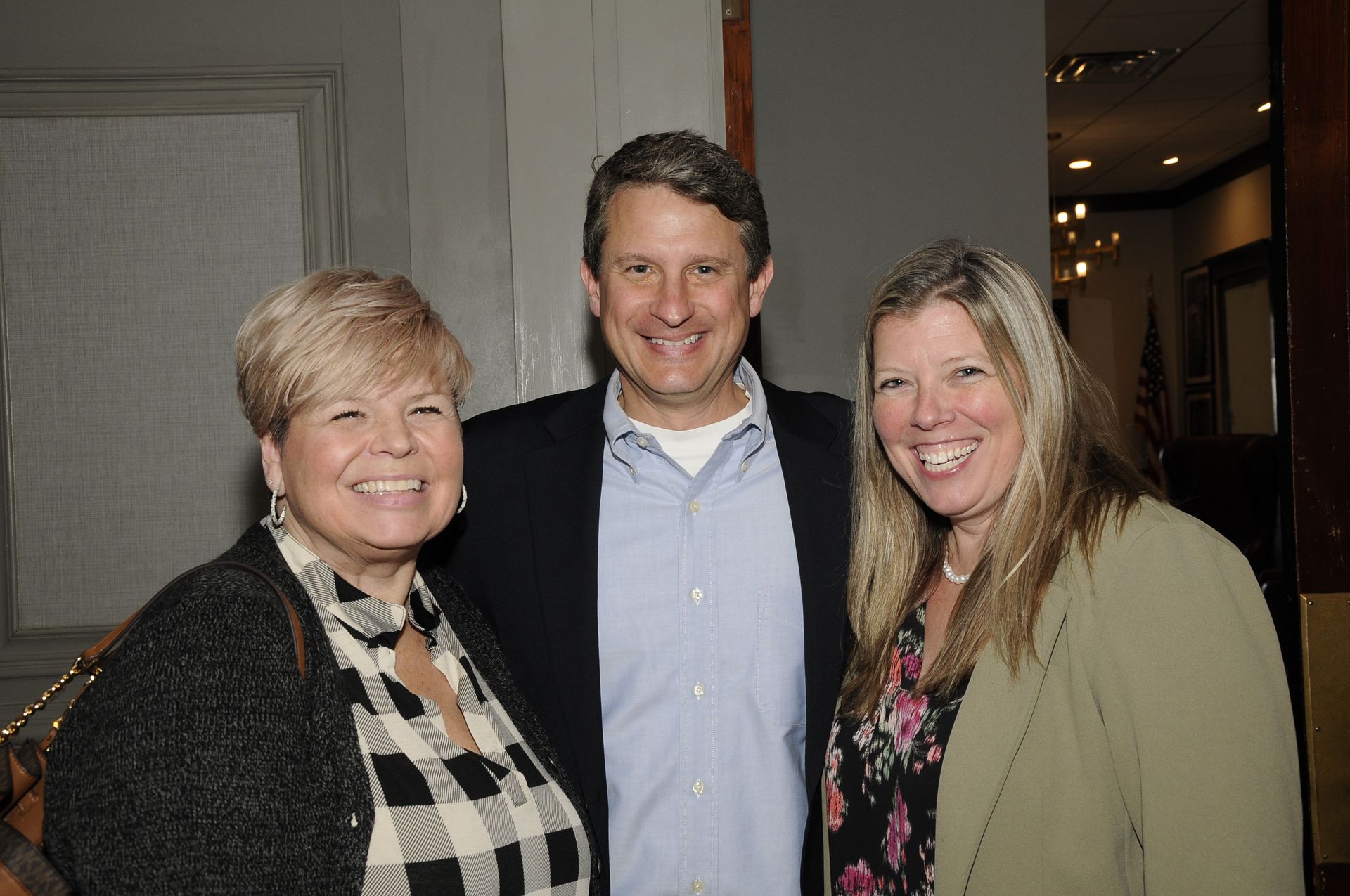 A man and two women are posing for a picture together and smiling.