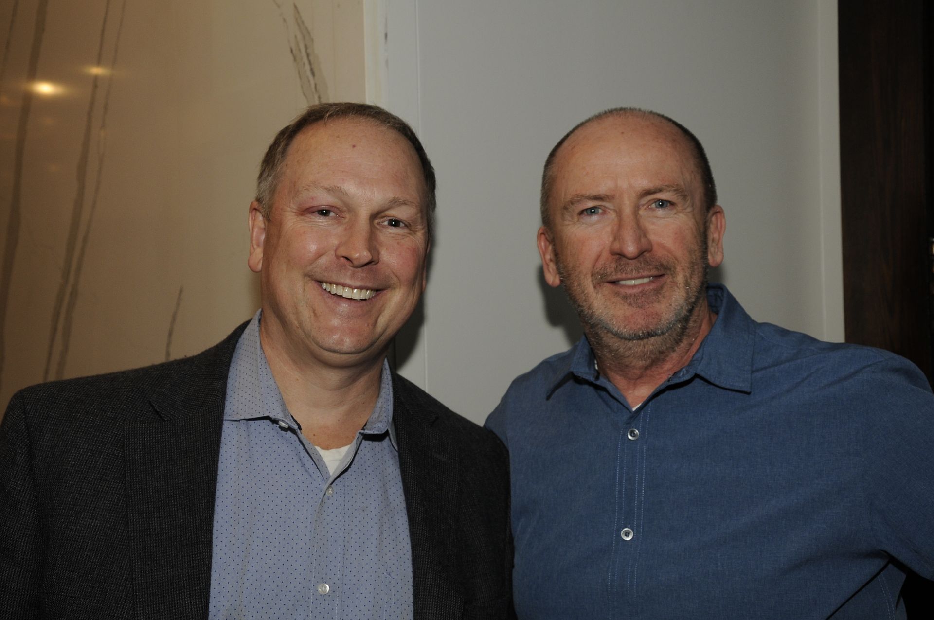 Two men are posing for a picture together and smiling for the camera.
