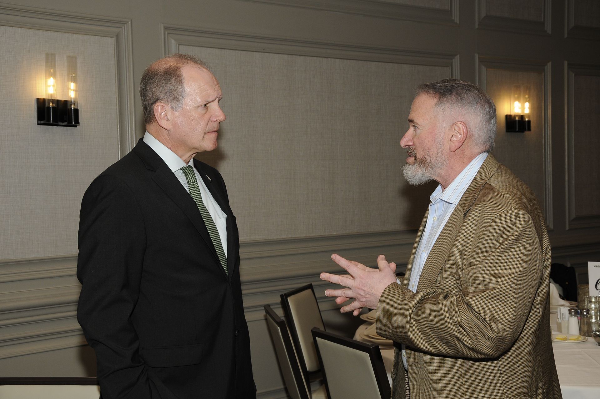 Two men in suits are talking to each other in a room.