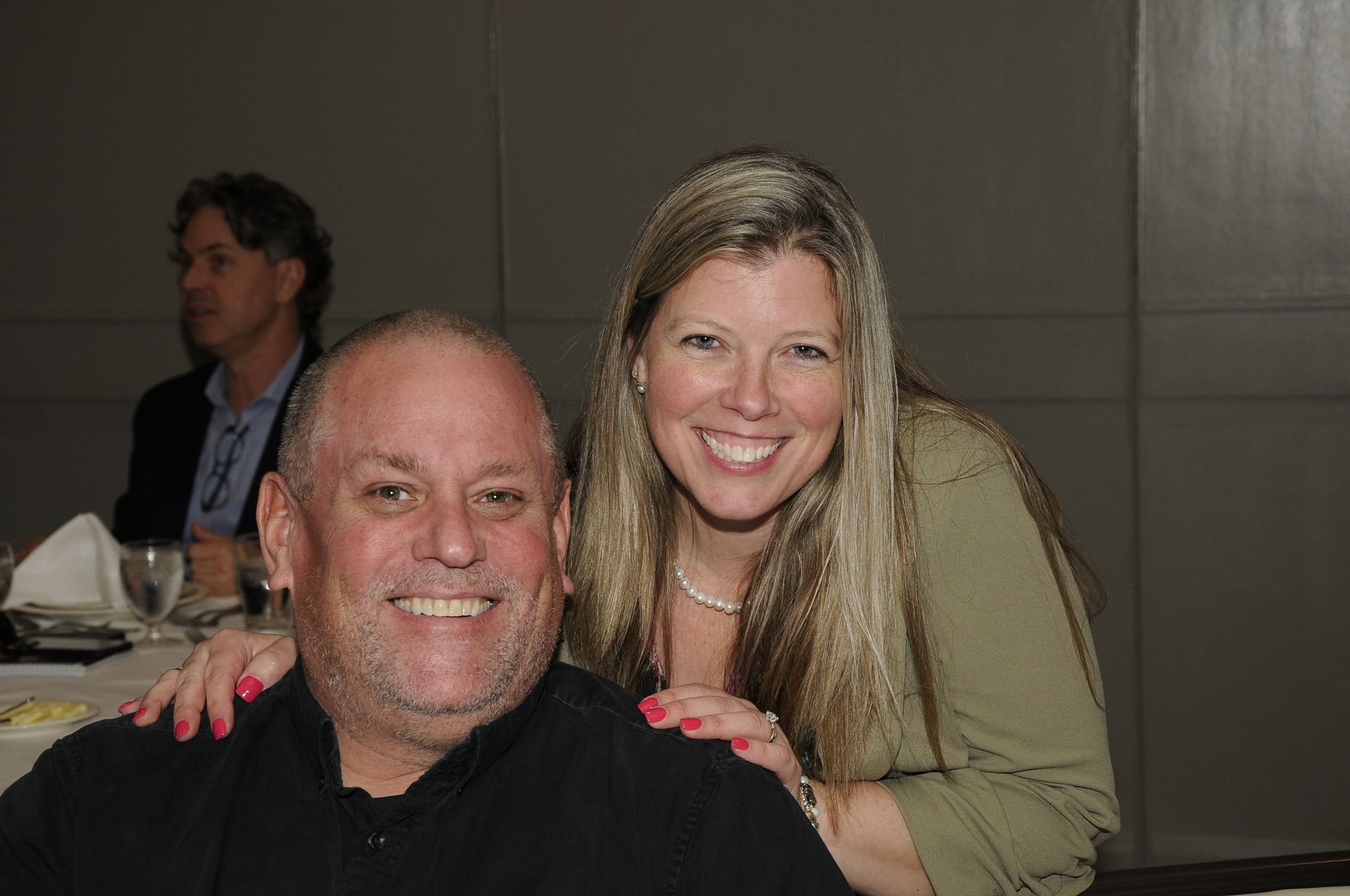 A man and a woman are posing for a picture while sitting at a table.