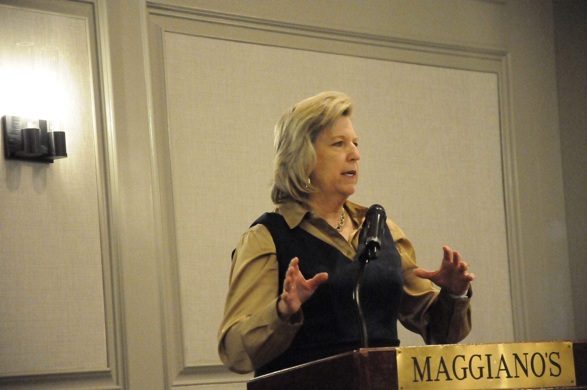 A woman stands behind a podium that says maggiano 's