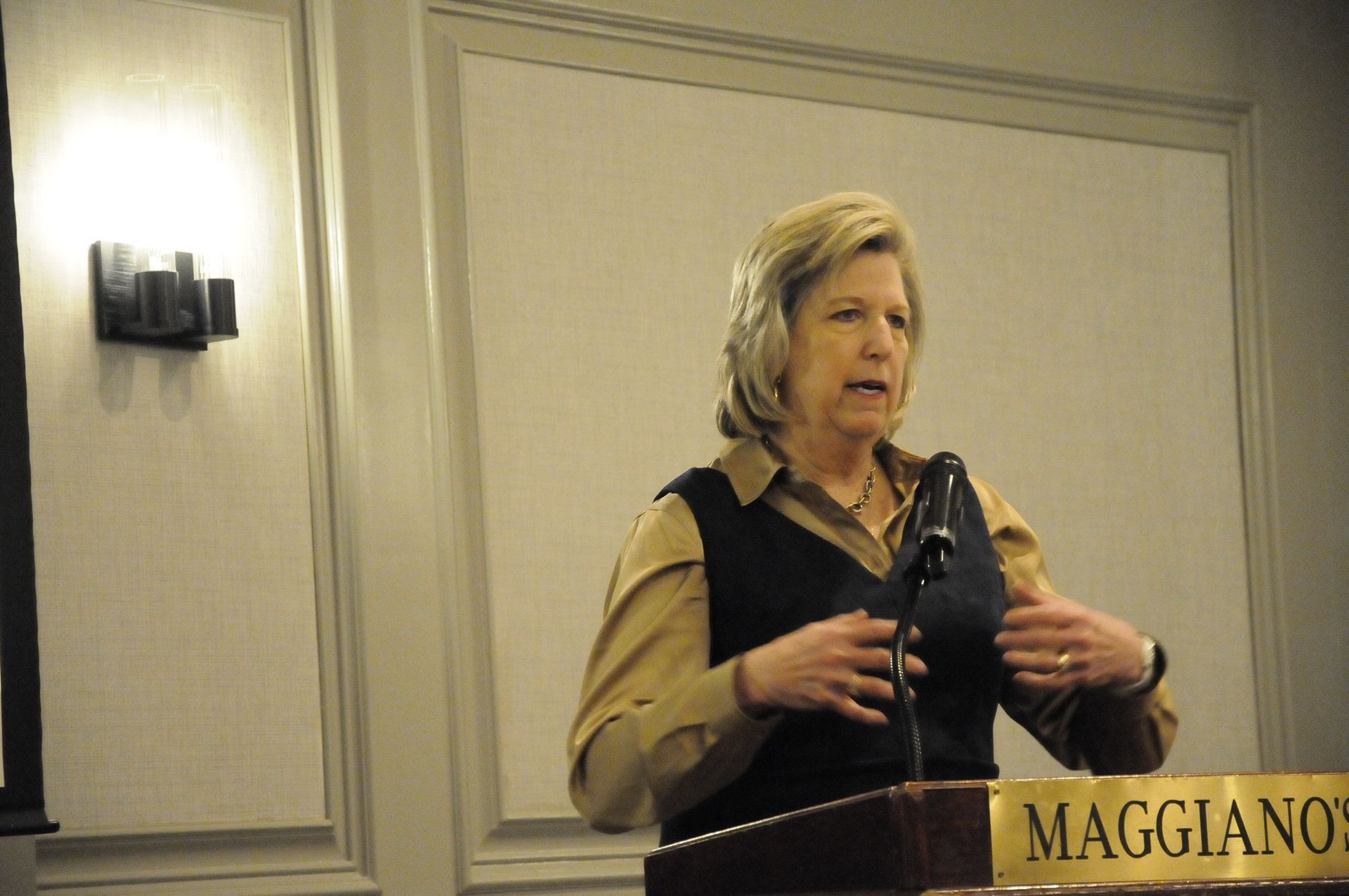 A woman stands at a podium that says maggiano on it