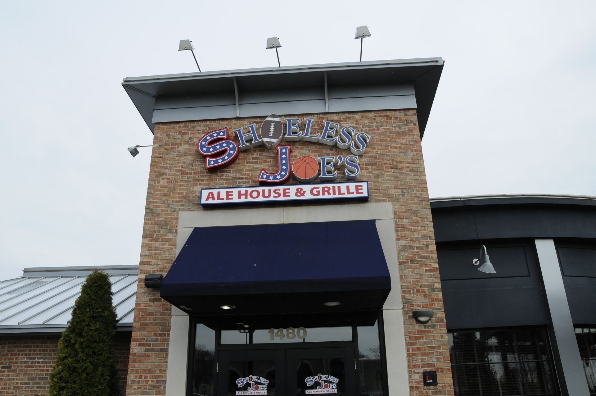 A brick building with a blue awning that says ballast point ale house & grill
