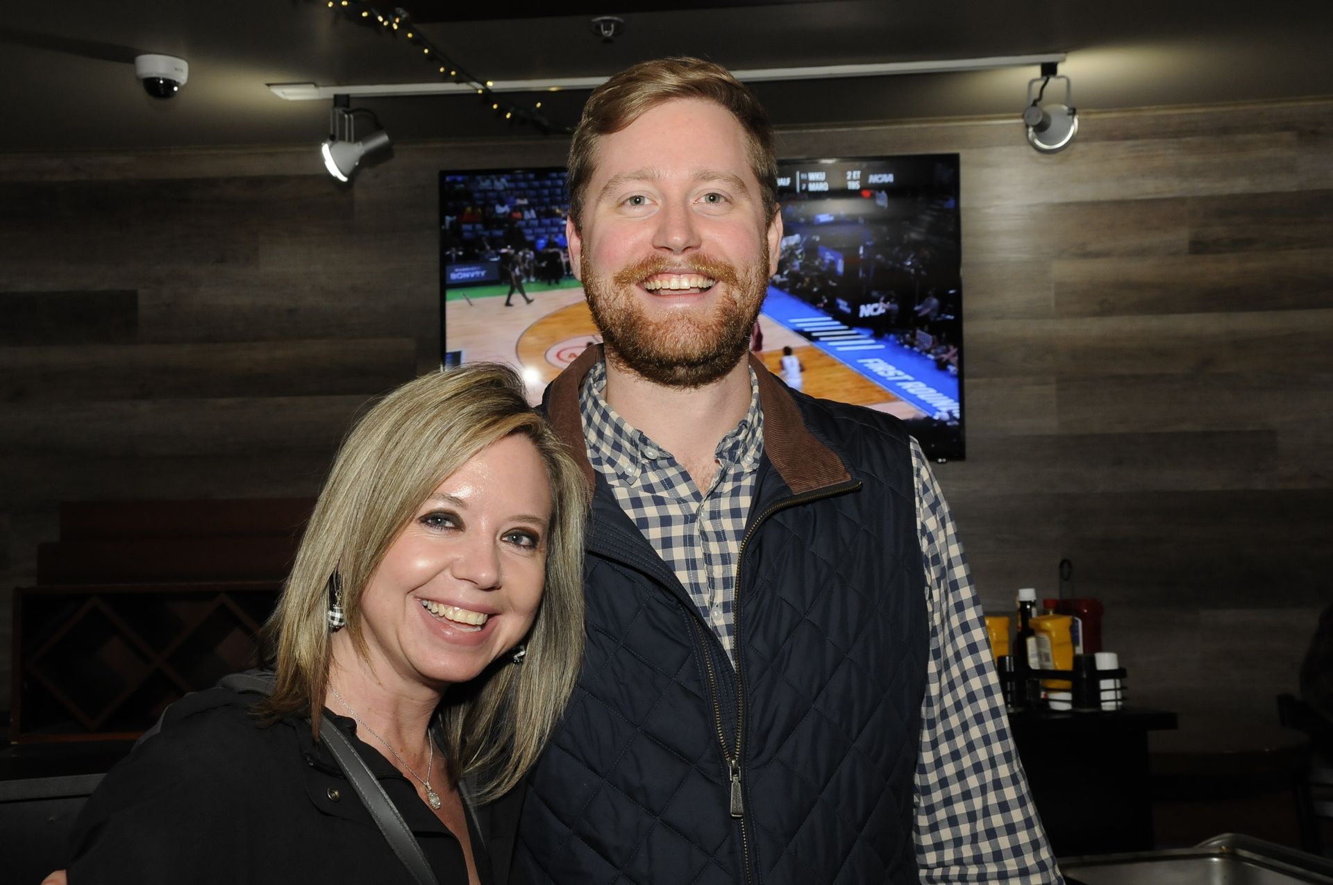 A man and a woman are posing for a picture in front of a television.