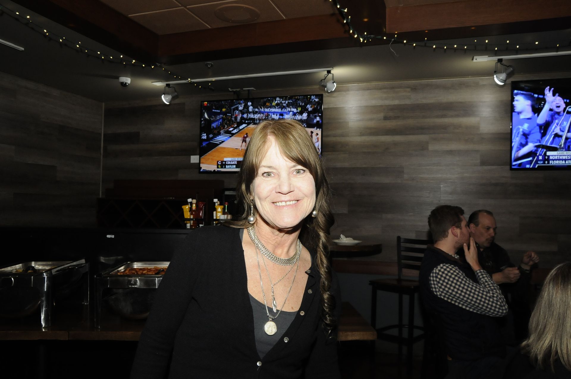 A woman is standing in front of a television in a bar.
