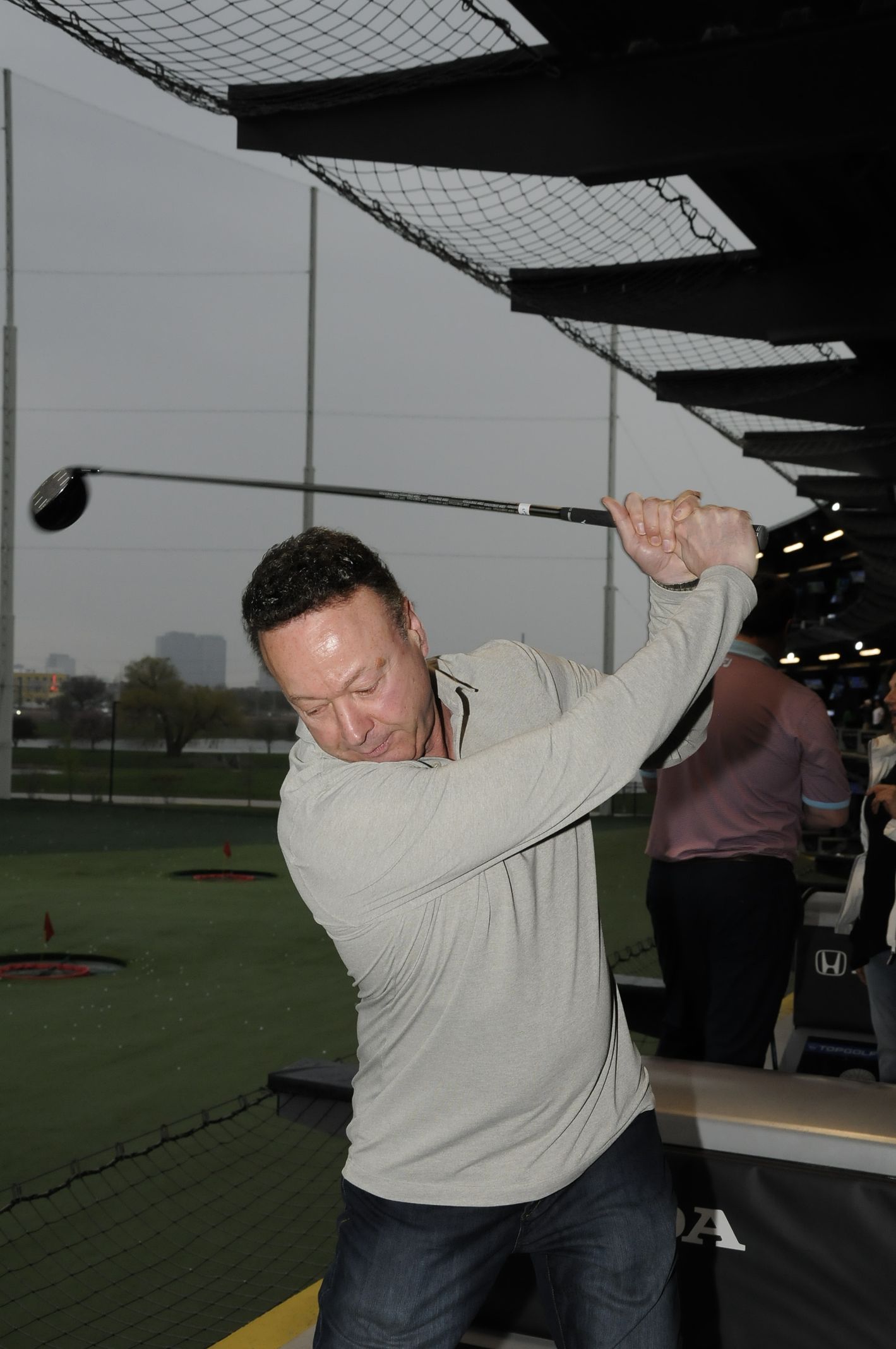 A man is swinging a golf club at a golf course