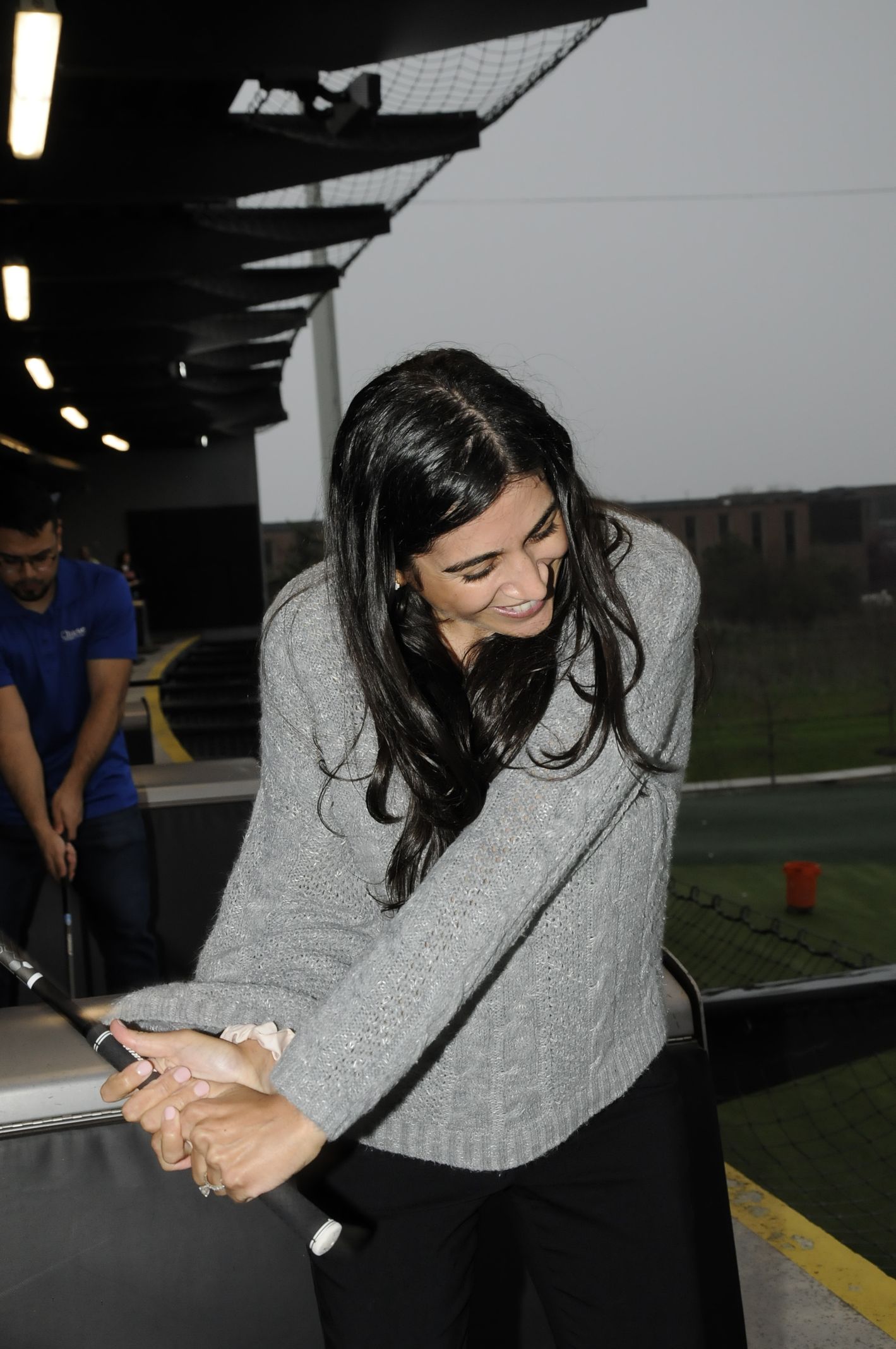 A woman is swinging a golf club at a golf course.