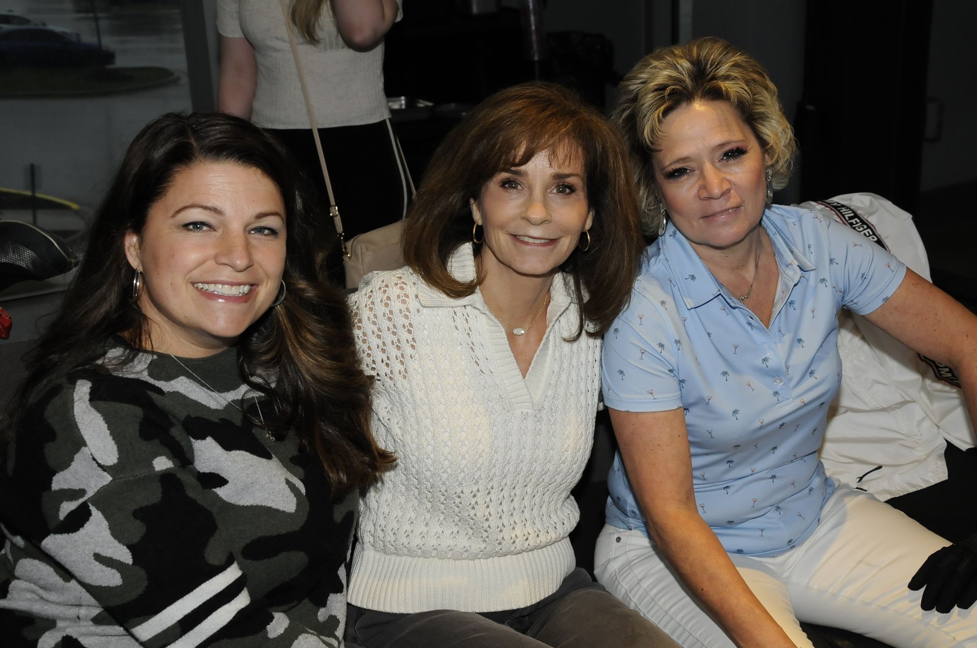 Three women are posing for a picture and smiling for the camera