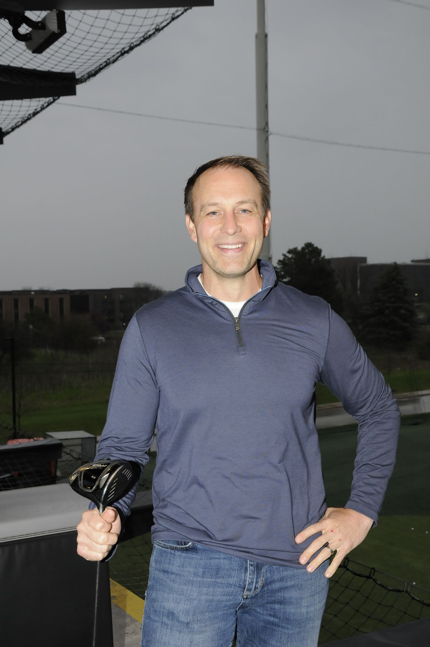 A man in a blue shirt is holding a golf club