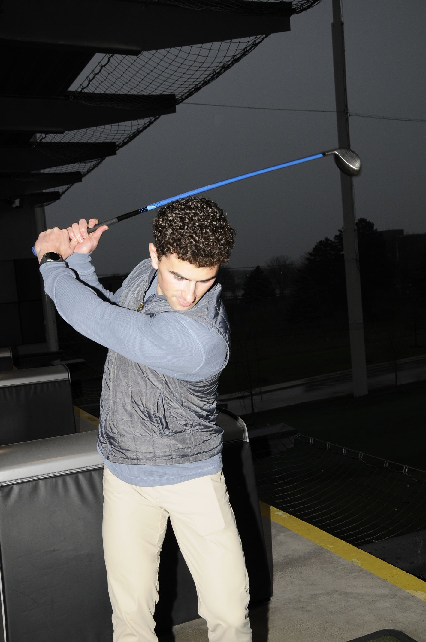 A man is swinging a golf club on a driving range