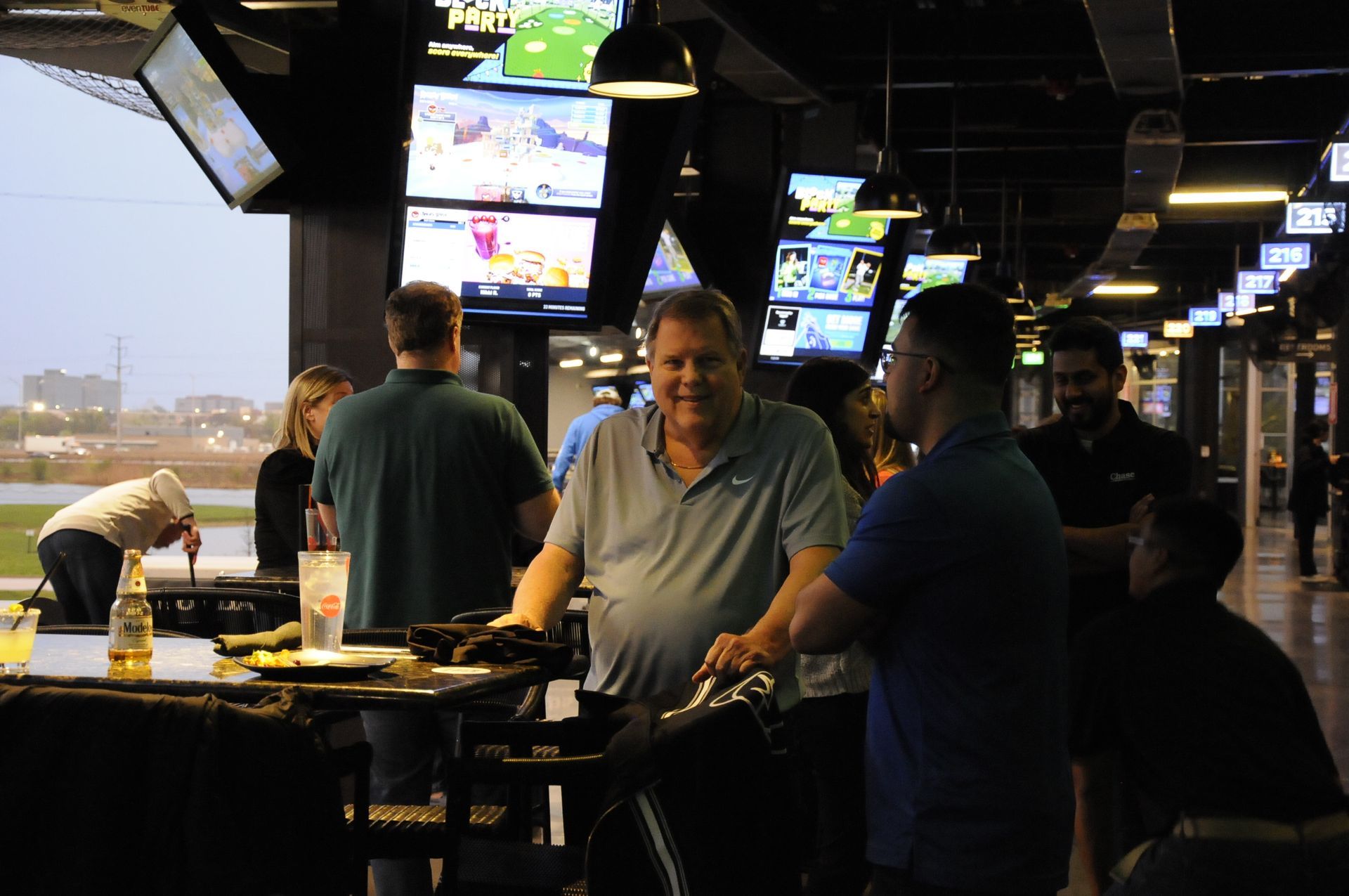 A group of men are sitting at tables in a restaurant talking to each other.